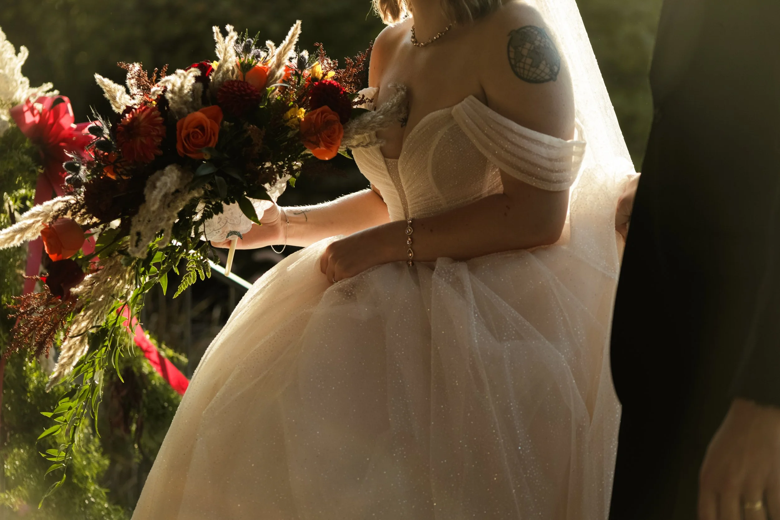 A bride in a wedding dress holding a bouquet of flowers during a wedding ceremony outdoors.
