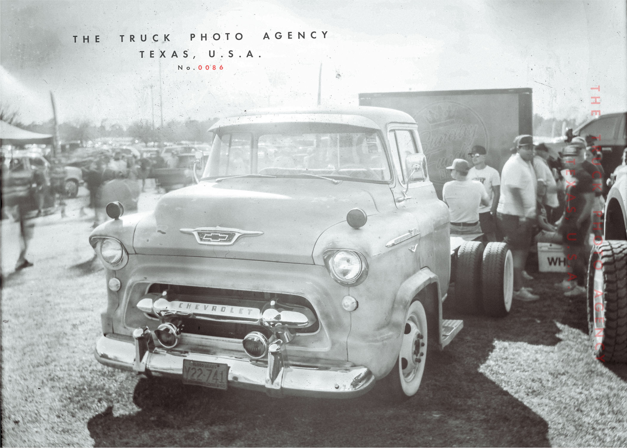 Vintage Chevrolet truck at an outdoor event with people gathered around in the background, black and white photo.