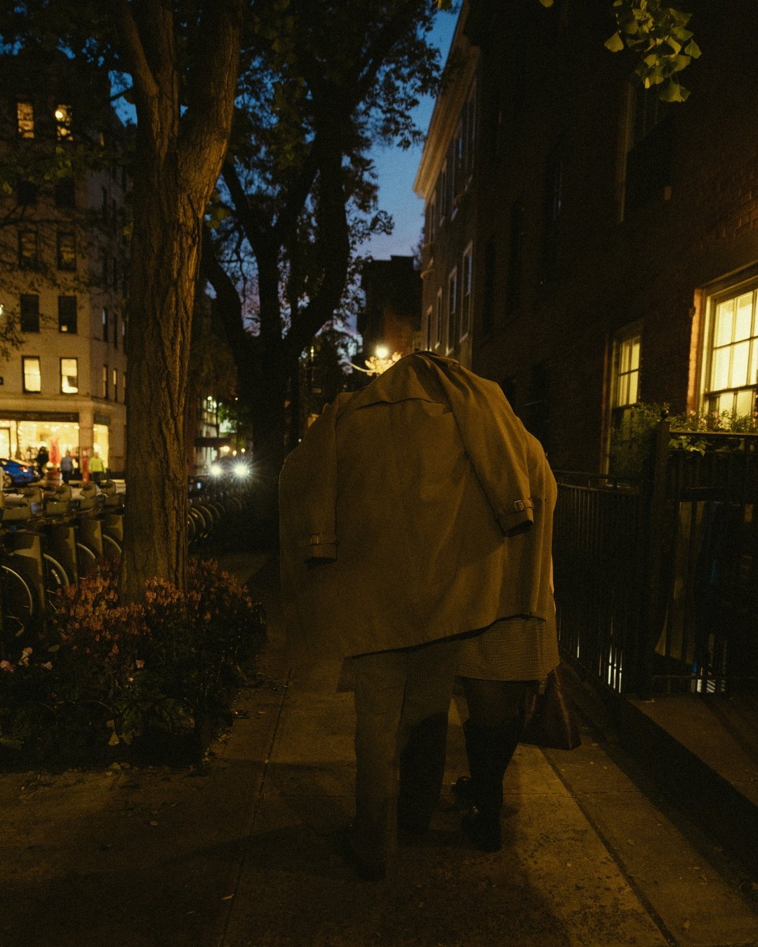 Couple cuddling under trench coat at night in West Village
