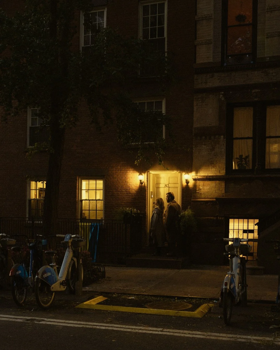 Couple standing at brick home doorway in West Village