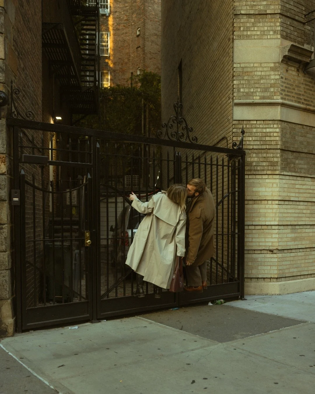 Couple kissing on swinging garage gate in West Village