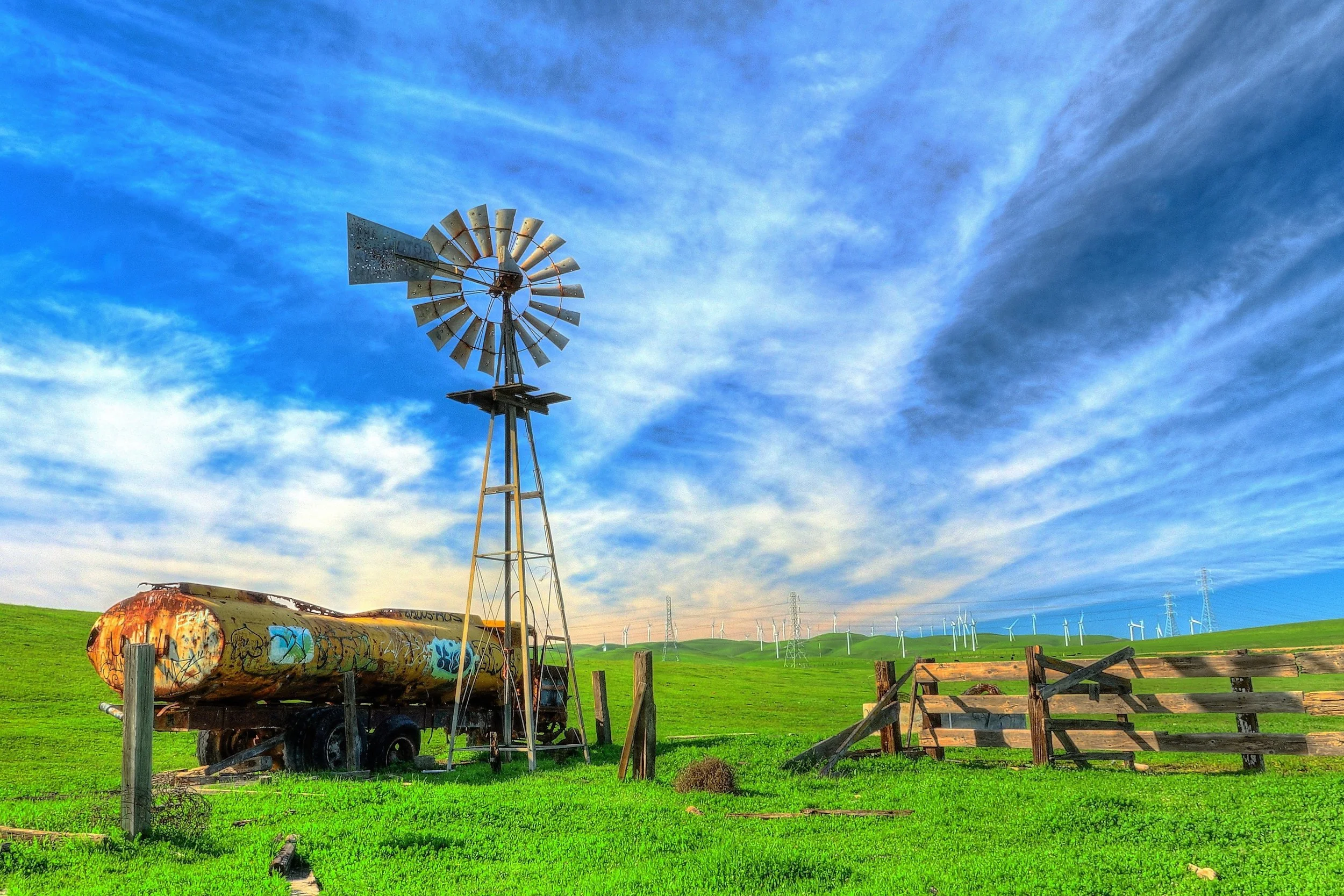 87-3 by Ken Sweezy.  

An abandoned tanker truck and solitary wind turbine in front of a modern wind turbine farm in the hills above Livermore.