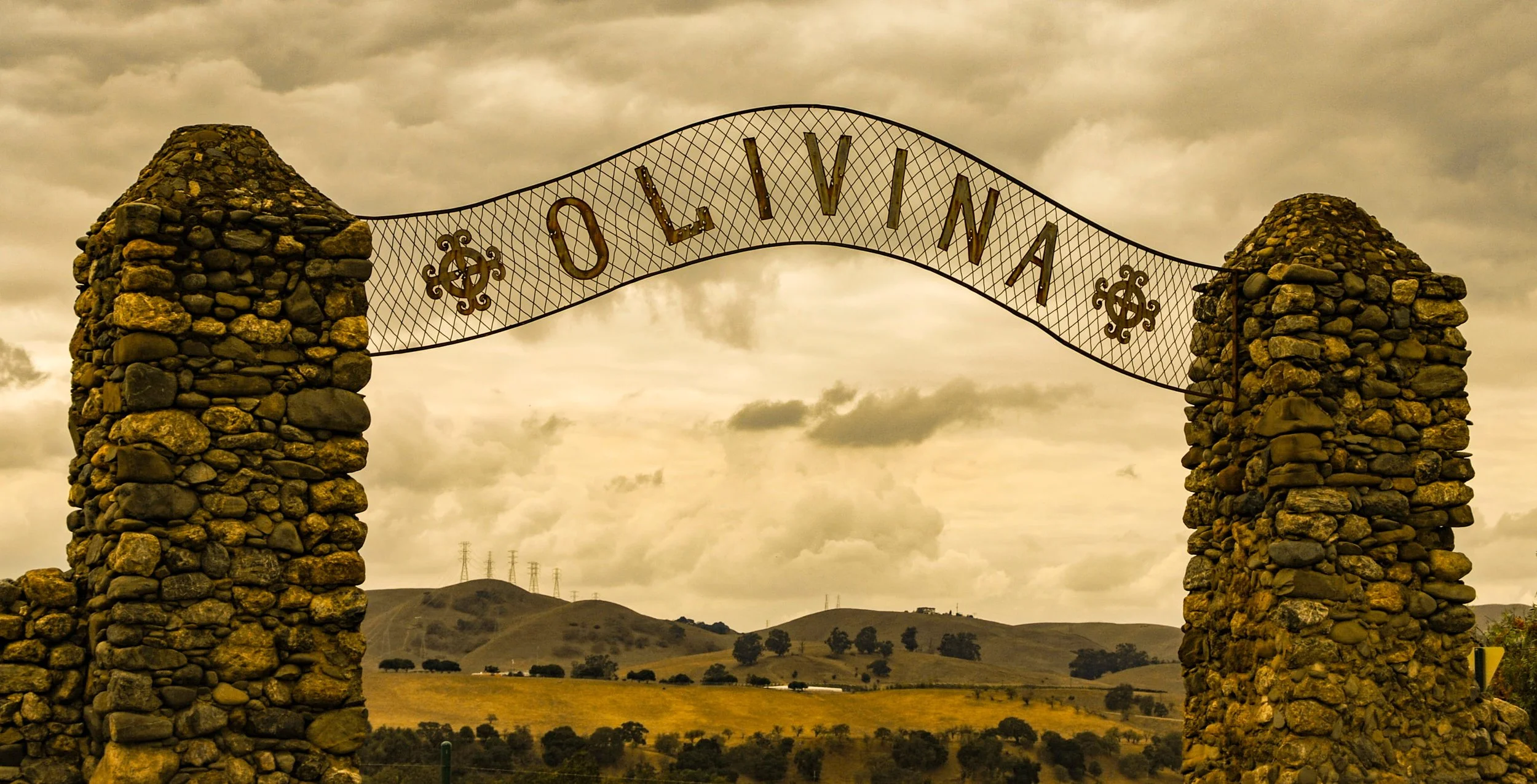 Olivina by Richard Finn.

 It’s really cool to see these old stone pillars still standing tall, holding up the Olivina sign just like they did back in the day. This is the original gateway to the Olivina ranch and vineyards. You can almost picture th