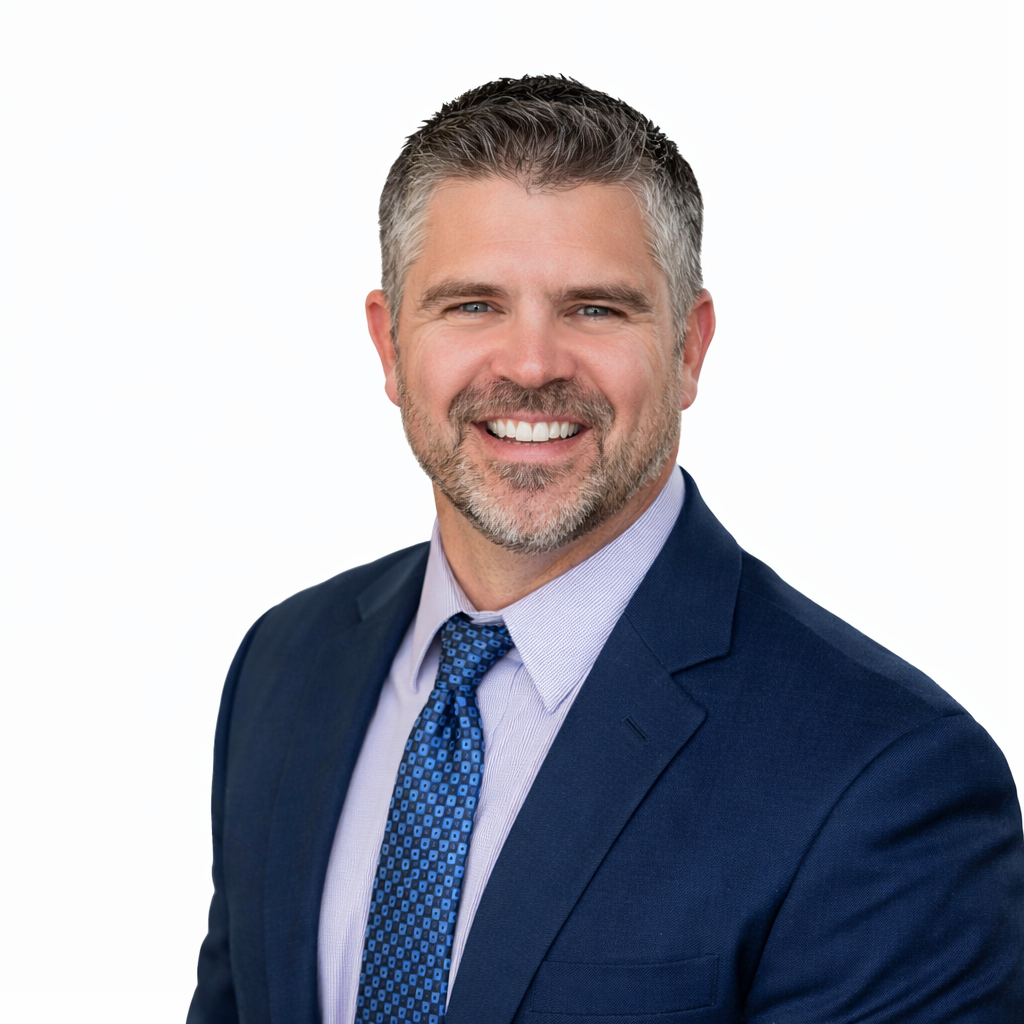 Man in blue suit and tie smiling against a neutral background.