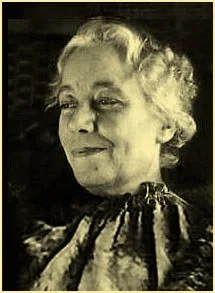 A black and white portrait of an elderly woman with curly hair, looking slightly to the side with a gentle expression.