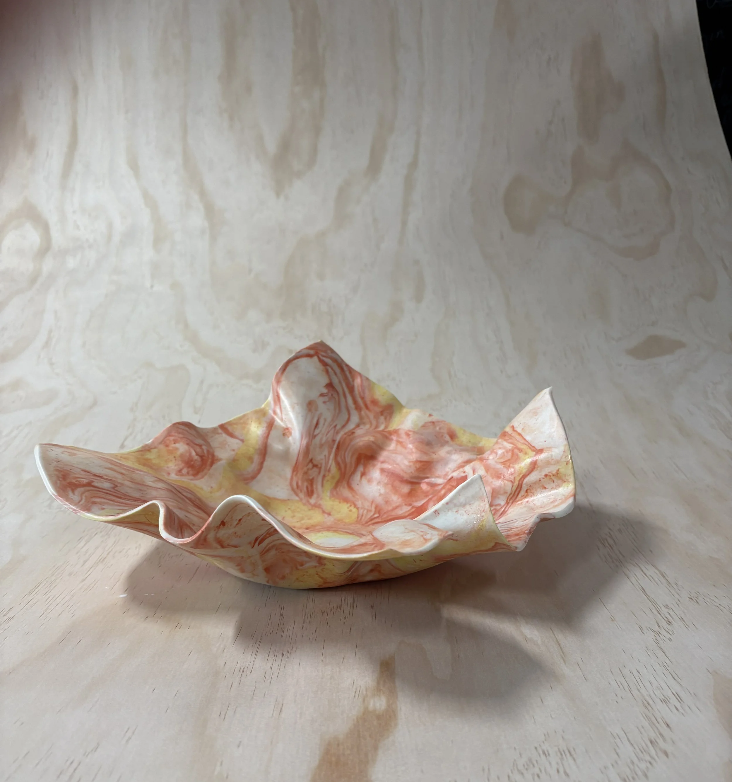 Michellè Benson Ceramics | Decorative Ceramic bowl with a marbled orange, yellow, and white pattern on a light wood surface with a light wood background.
