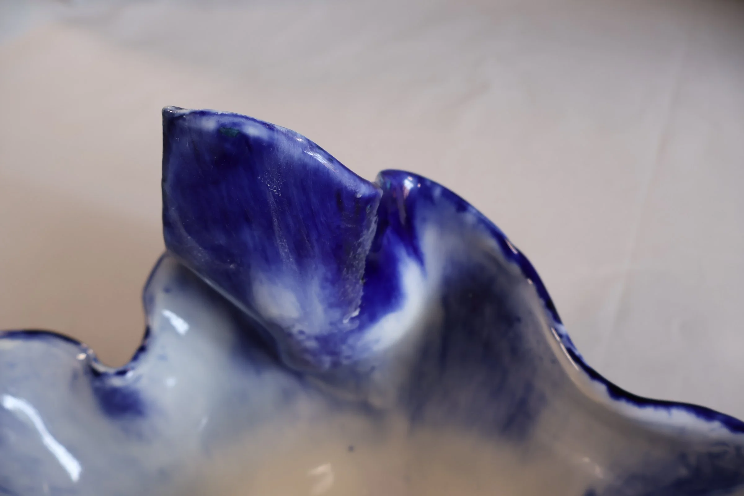 Close-up of a blue and white ceramic object with smooth, glossy surface and irregular edges.