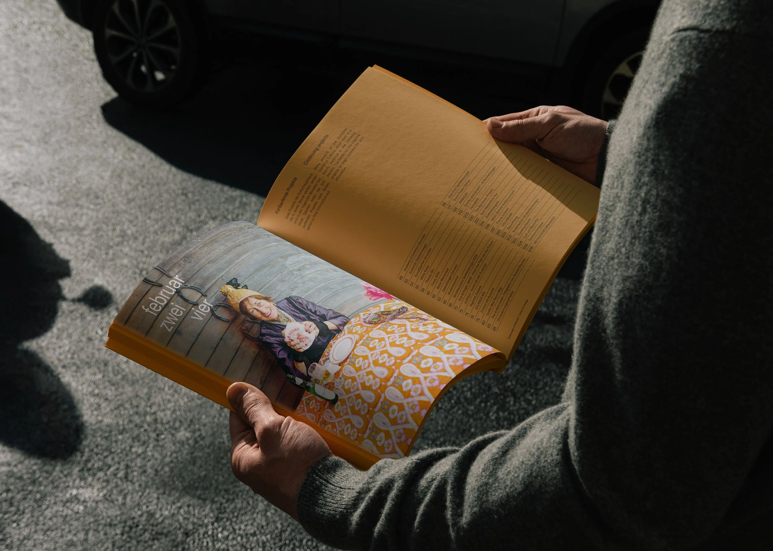 Jemand hat das Kulturhauptstadt Magazin aufgeschlagen und liest daraus, inszeniert vom Studio für Branding Doppelpaula.