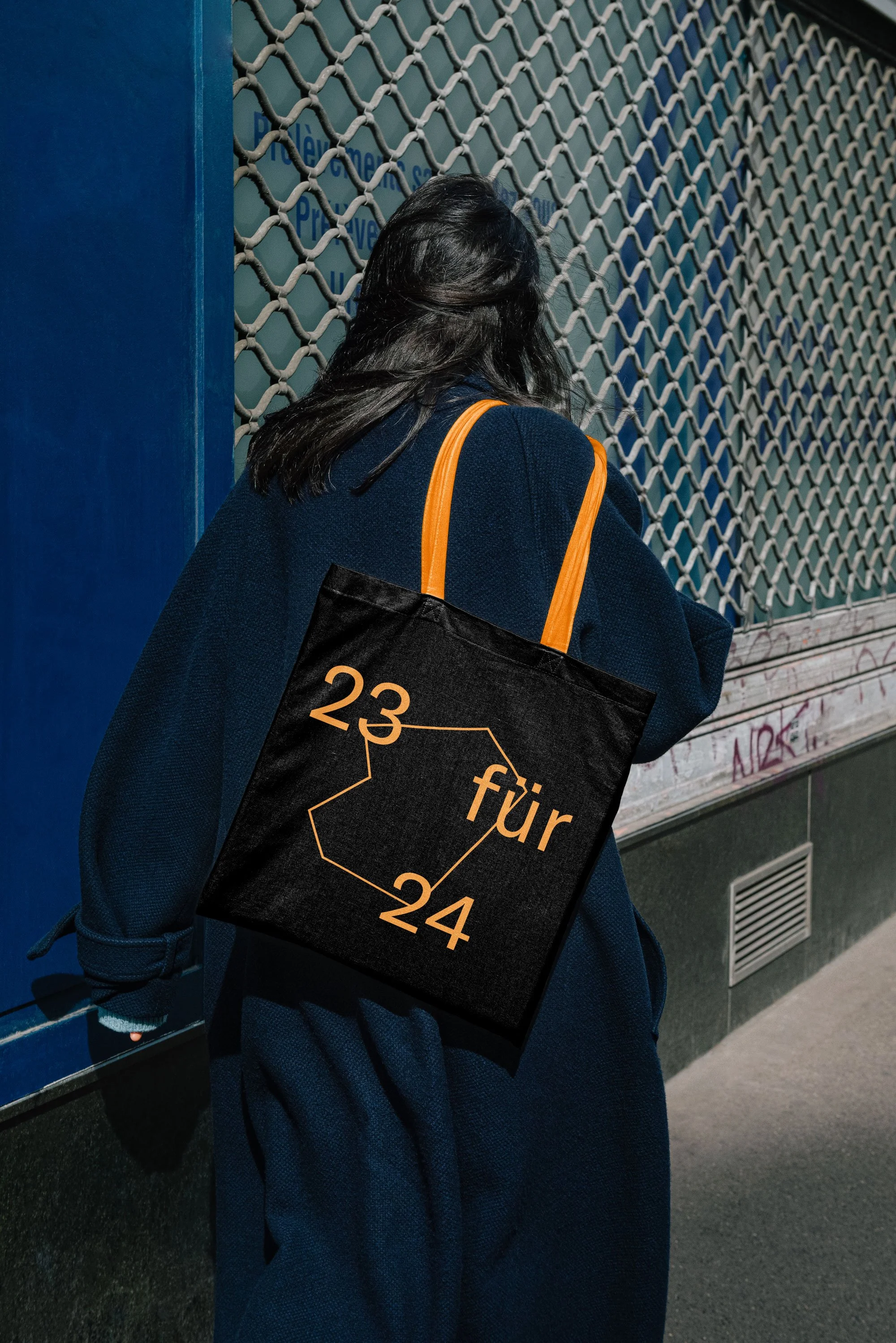 Eine Dame trägt ein Tote Bag von der Kulturhauptstadt auf der Schulter und ist der Kamera abgewandt, inszeniert vom Studio für Branding Doppelpaula.