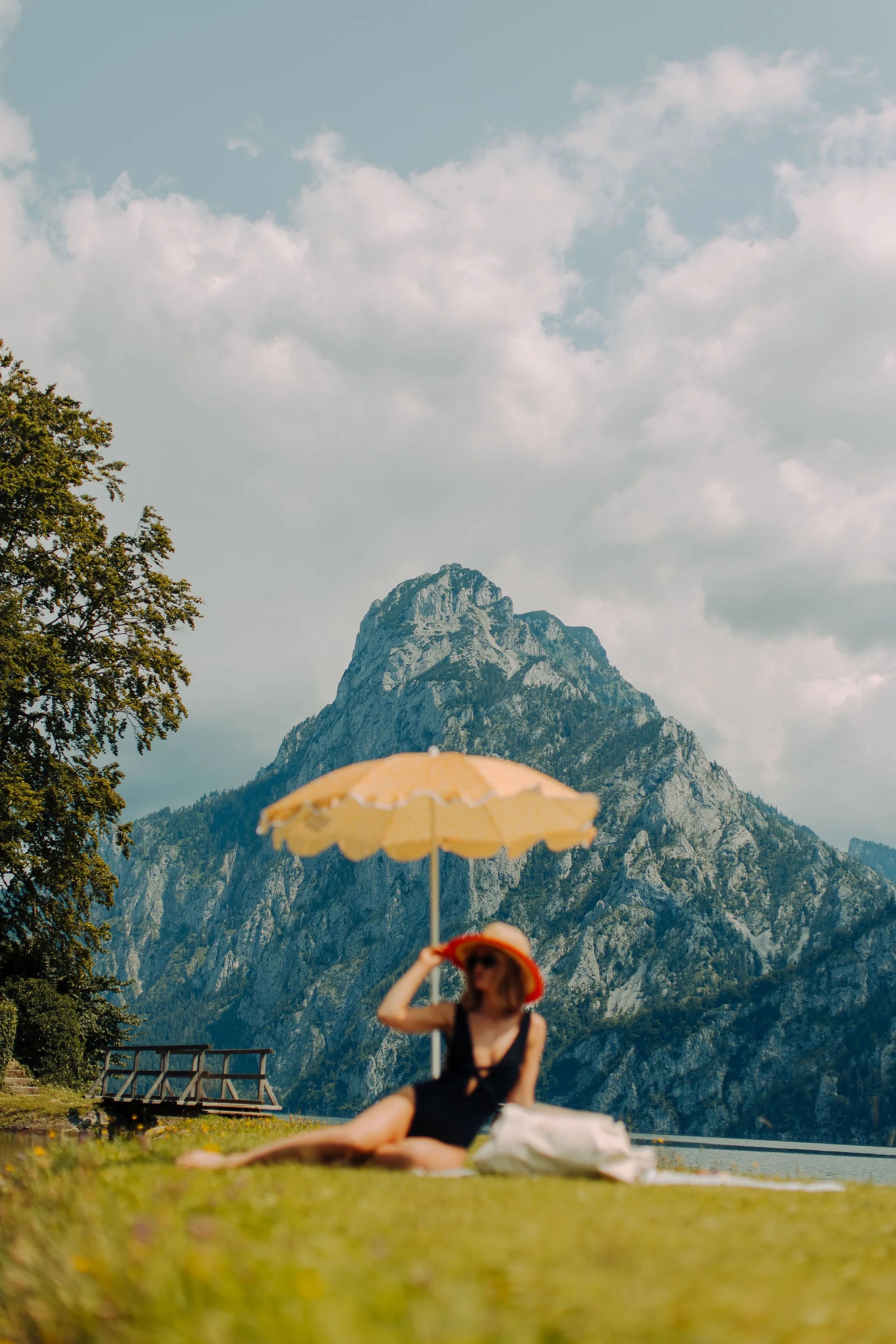 Eine Person sitzt auf der Wiese, im Hintergrund sieht man die Berge, inszeniert vom Studio für Branding Doppelpaula.