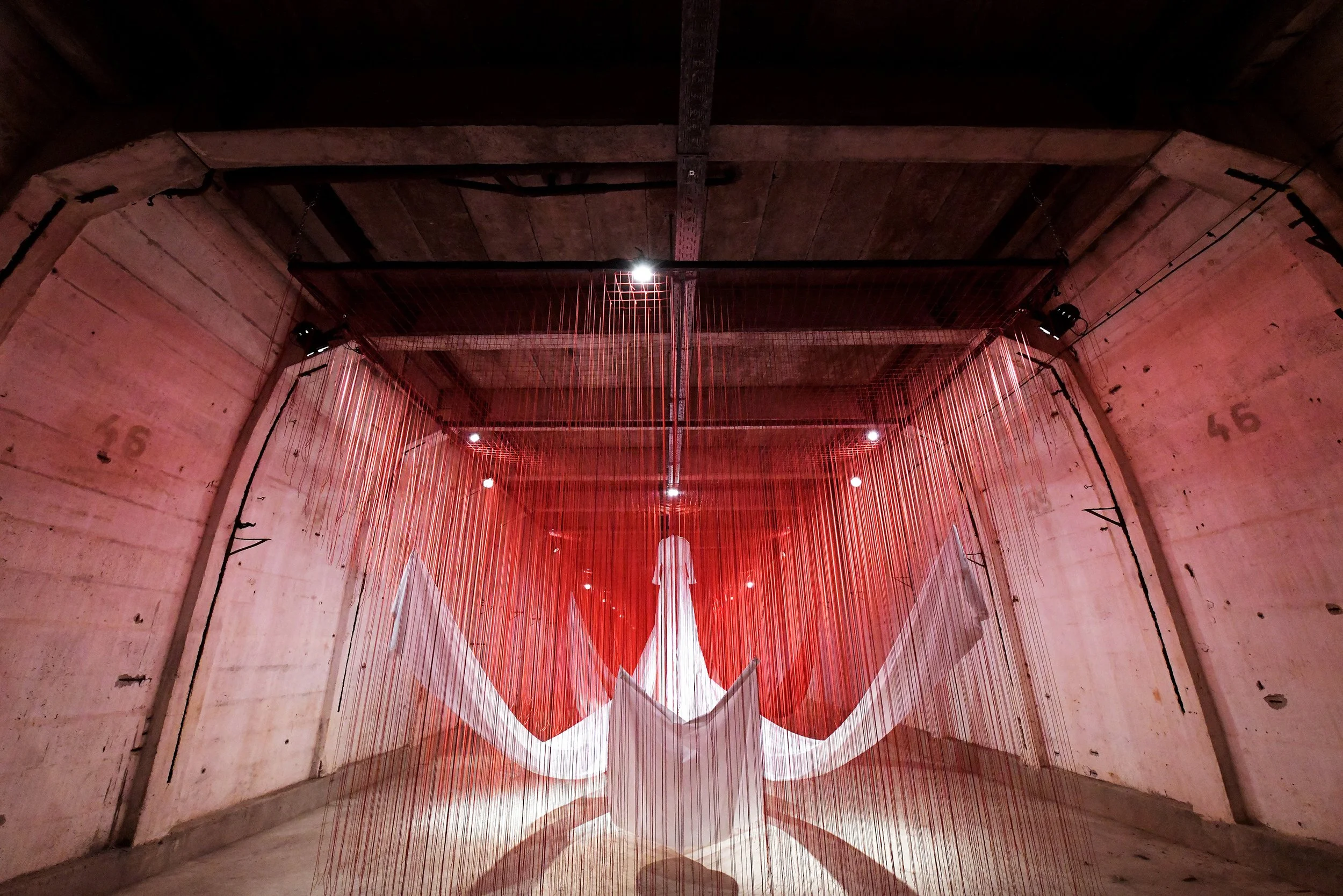 Weißer Stoff und rote Fäden hängen von der Decke, inszeniert vom Studio für Branding Doppelpaula. Kunstwerk von Chiharu Shiota