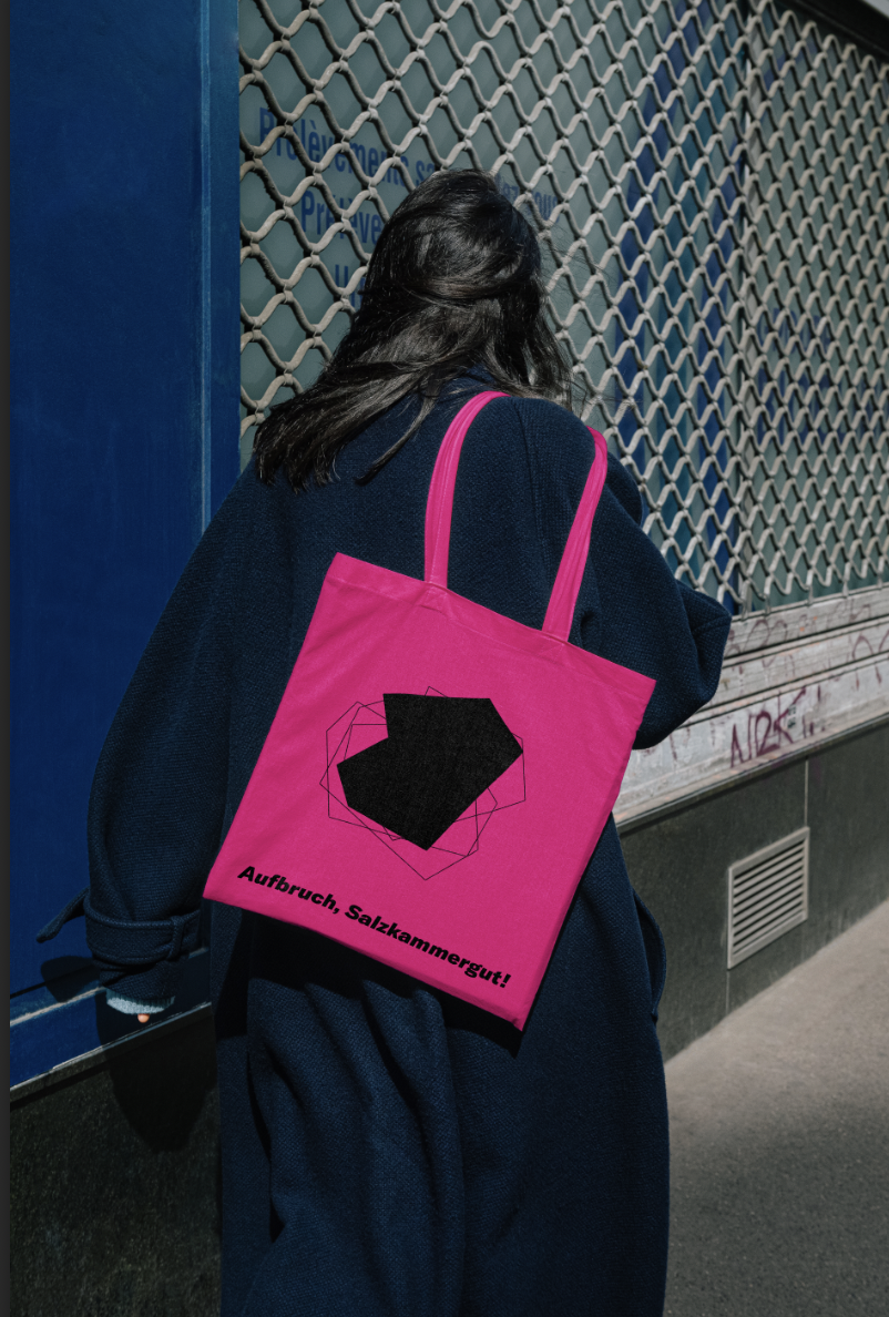 Eine Dame hat ein Merch Tote Bag von Aufbruch Salzkammergut auf der Schulter, steht mit dem Rücken zur Kamera, inszeniert vom Studio für Branding Doppelpaula. 