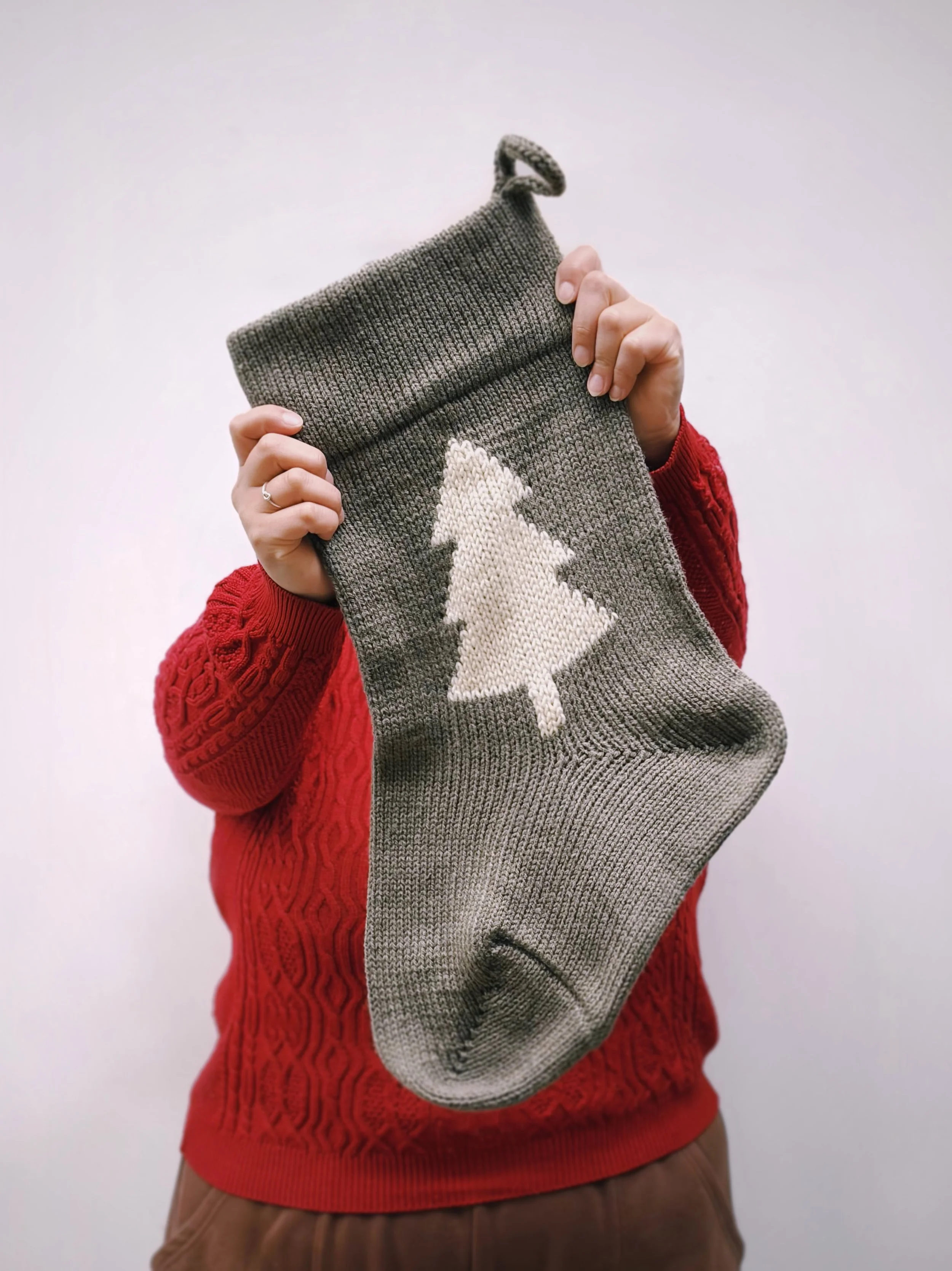 Person holding up a handmade machine knitted Christmas stocking showcasing Loré Loré’s festive knitting workshop in Melbourne.