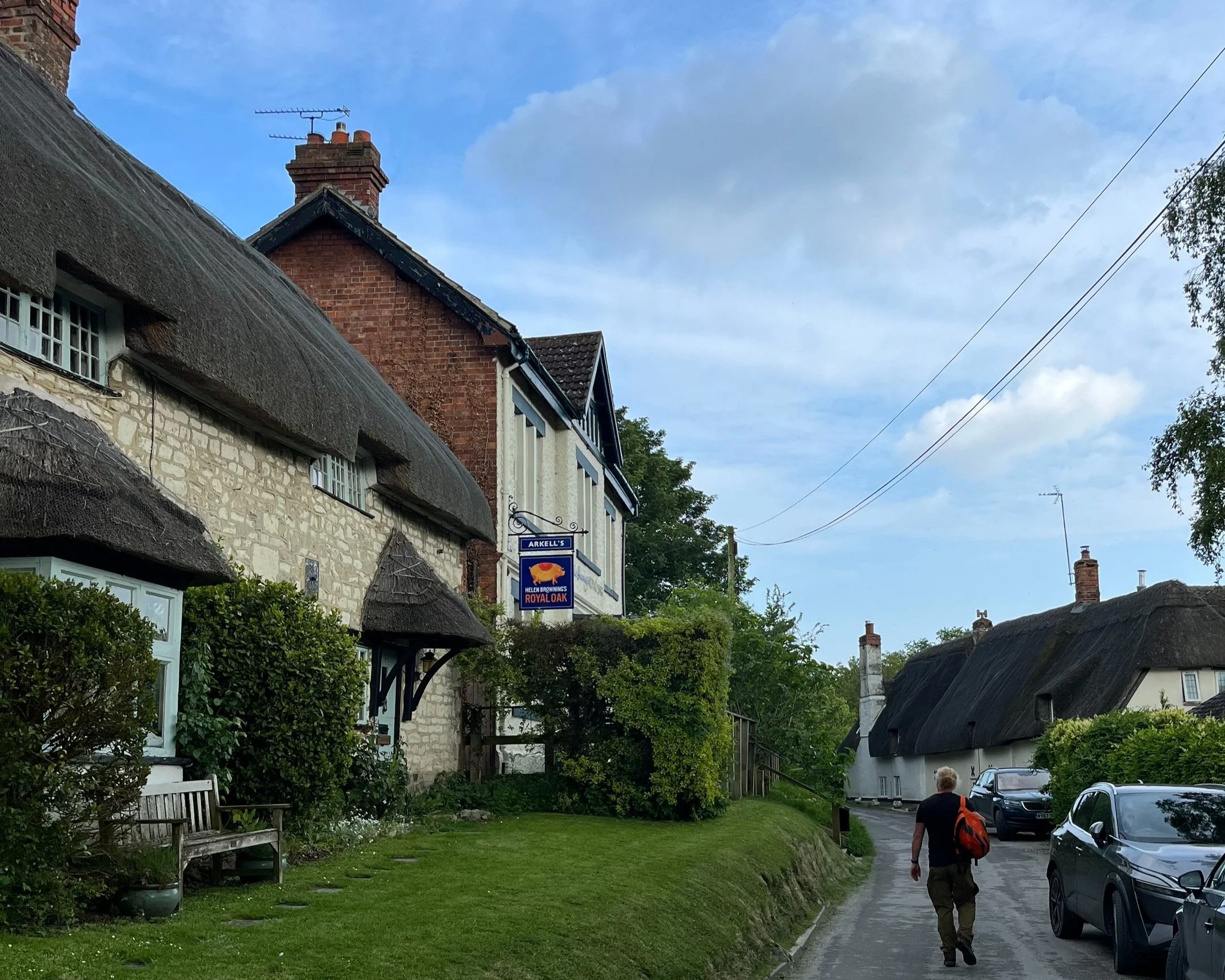 Helen Browning's Royal Oak pub with thatched cottage and hiker walking towards it.  Idyllic English Village