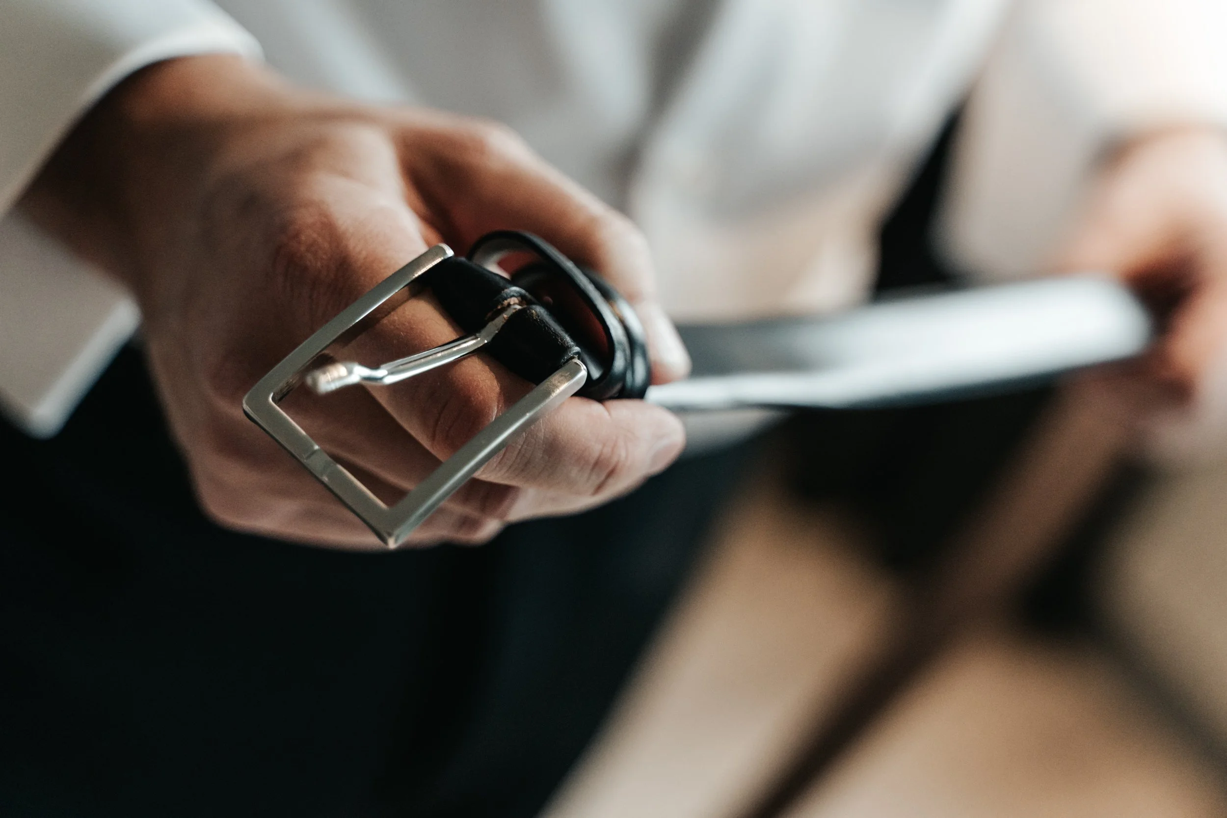 Man holding a black leather belt buckle in his hand.