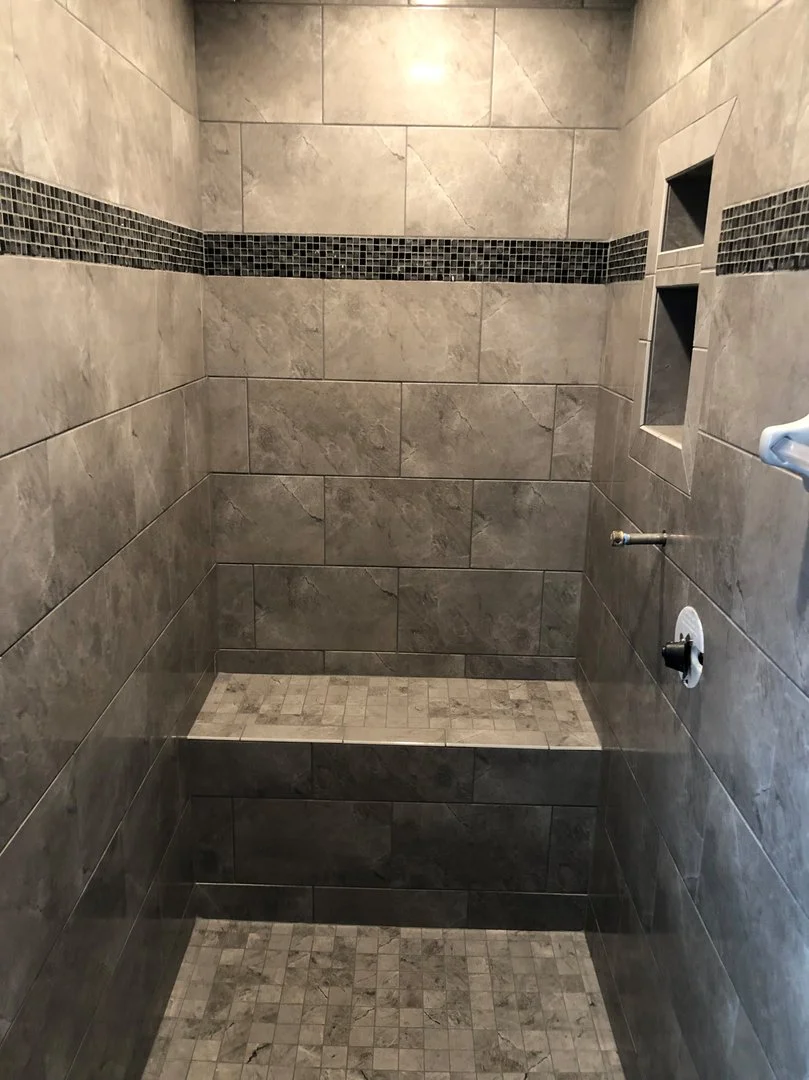 Modern tiled shower interior with built-in shelf and bench.