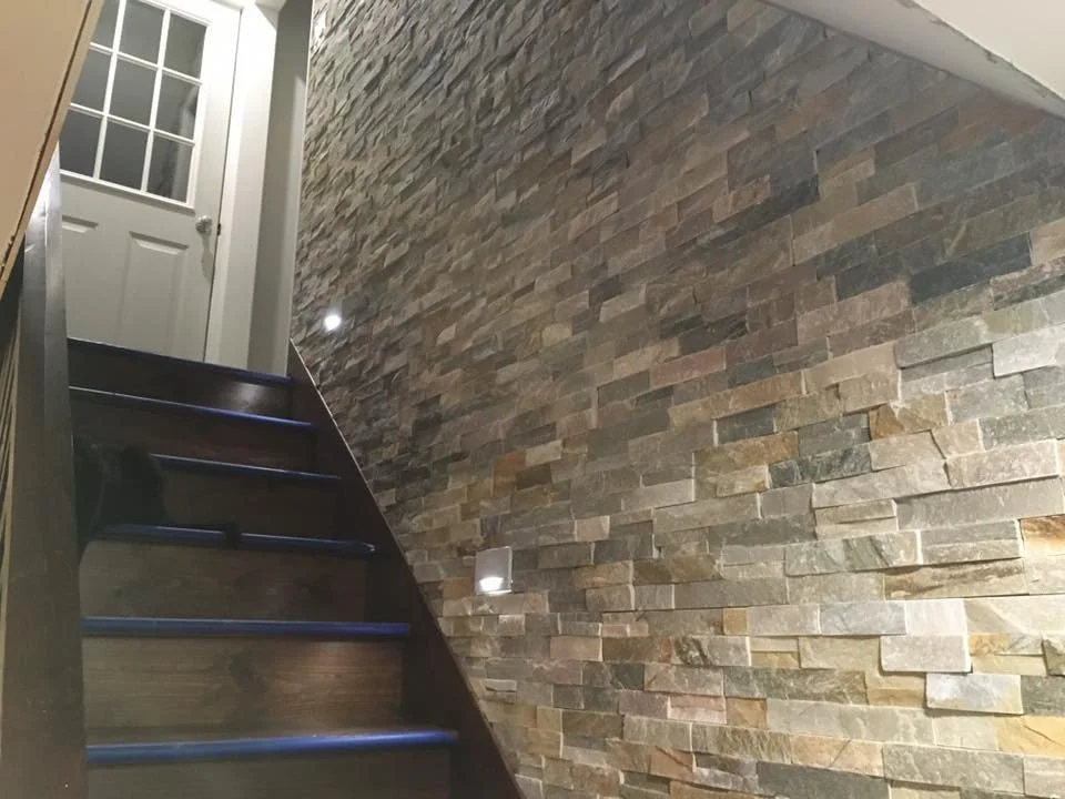 Indoor staircase with stone accent wall and wooden steps leading to a door