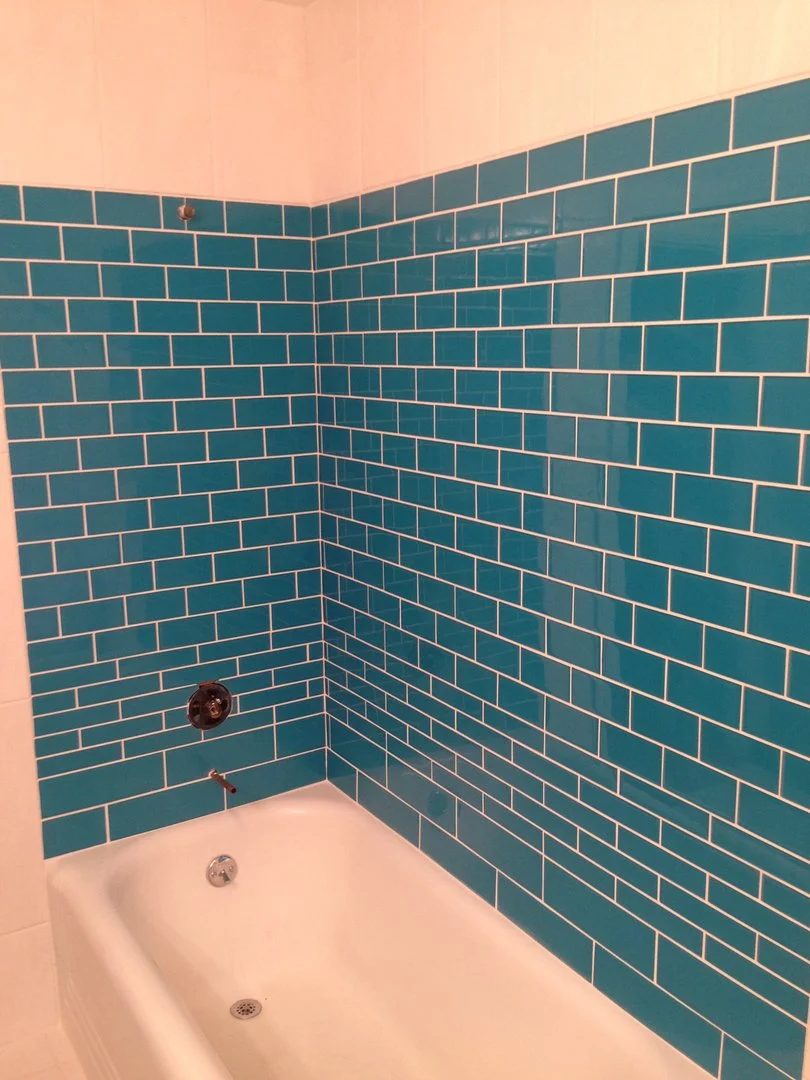 Bathroom with turquoise subway tiles and a white bathtub