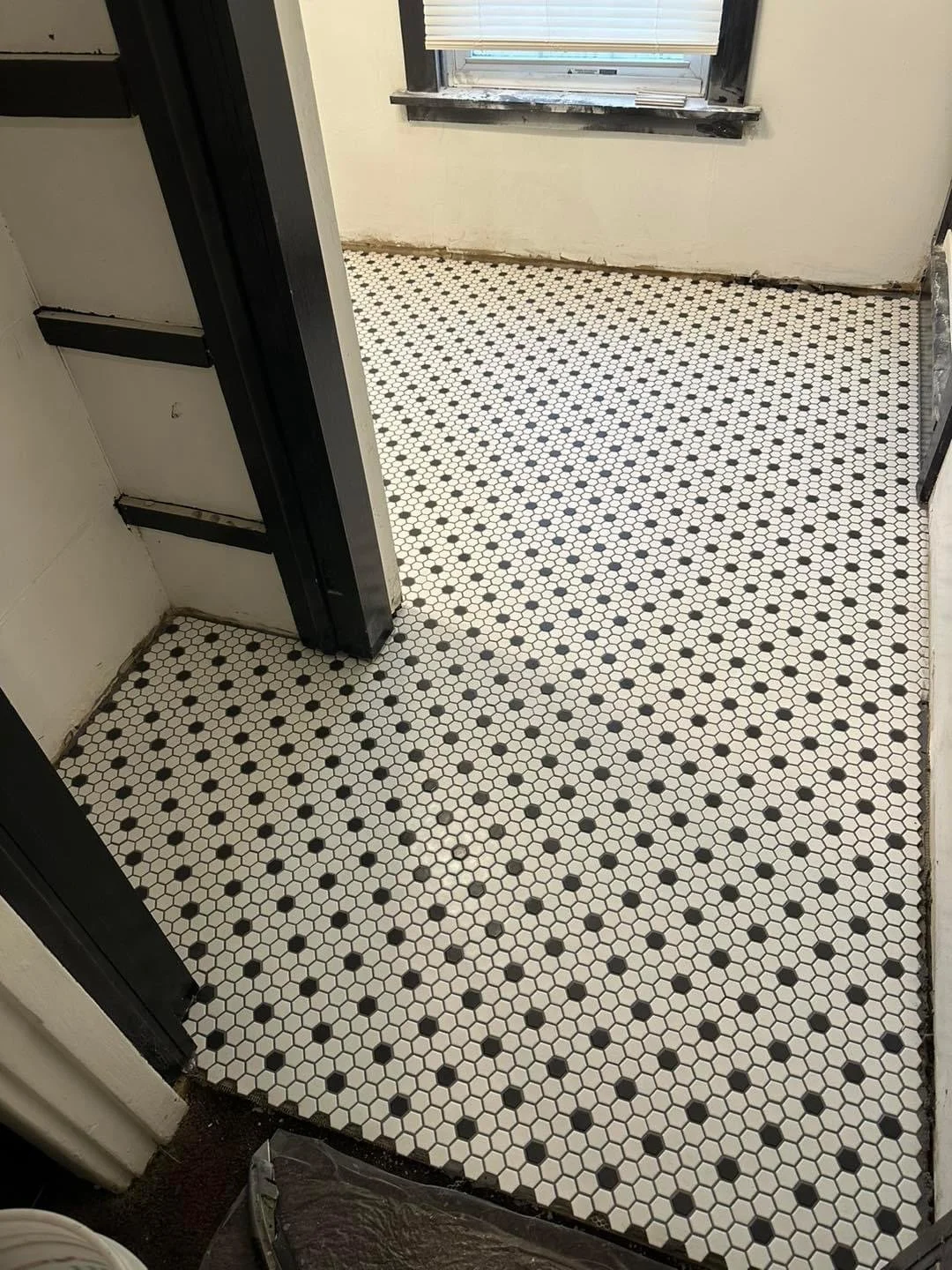 Room with white and black hexagonal tile flooring, white walls, and a window with blinds.