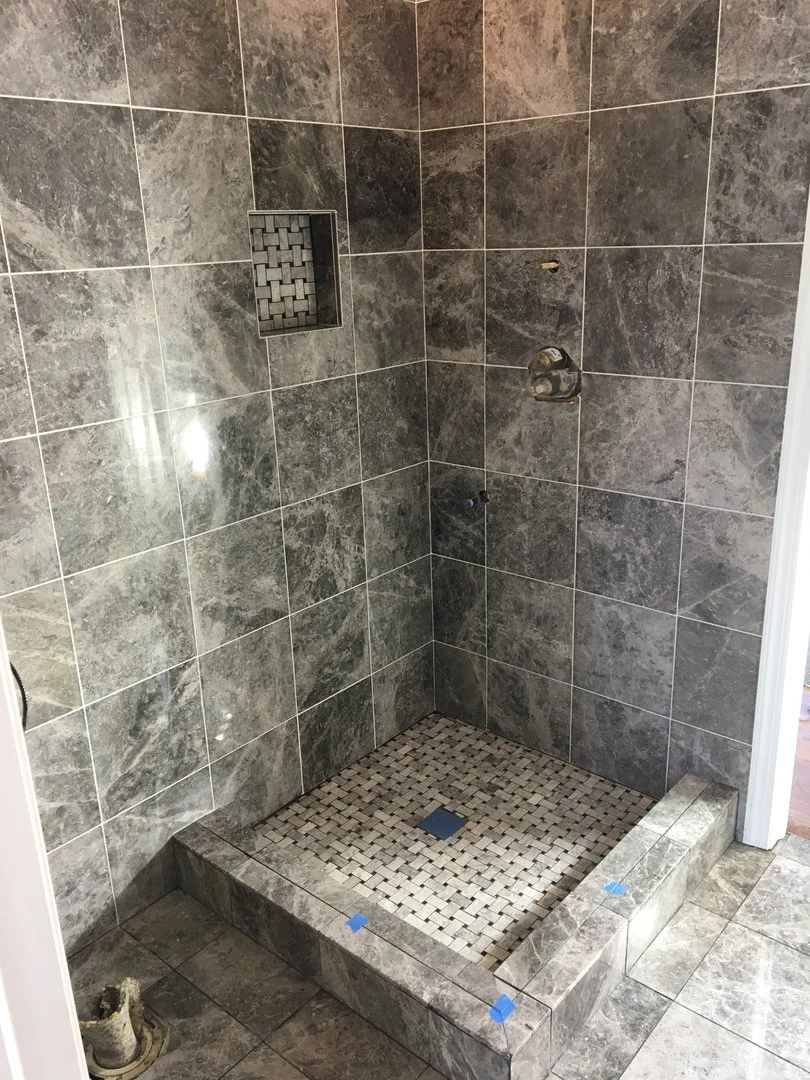 Unfinished bathroom with gray tile shower and floor