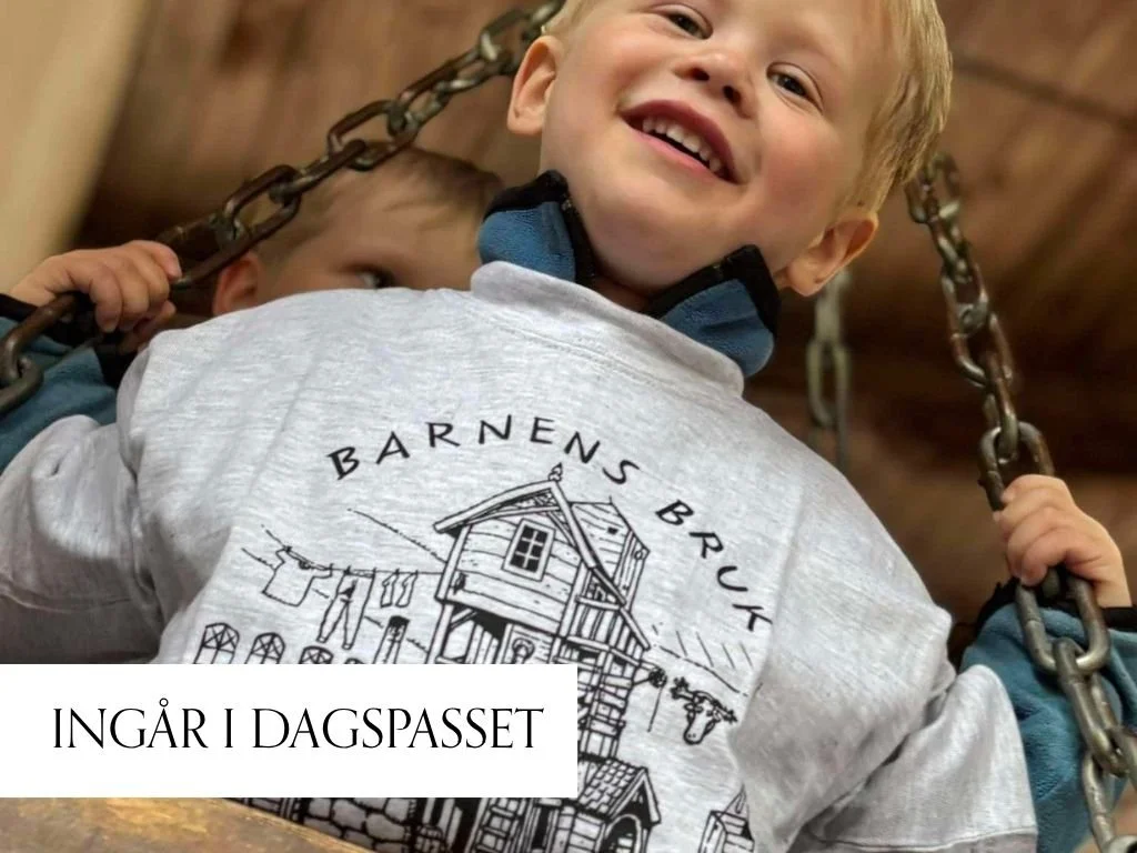 Två barn utomhus, en pojke i grönt skynke och randig tröja, en flicka med bandana, står framför ett hus med en skylt som säger "Barnens bruk".