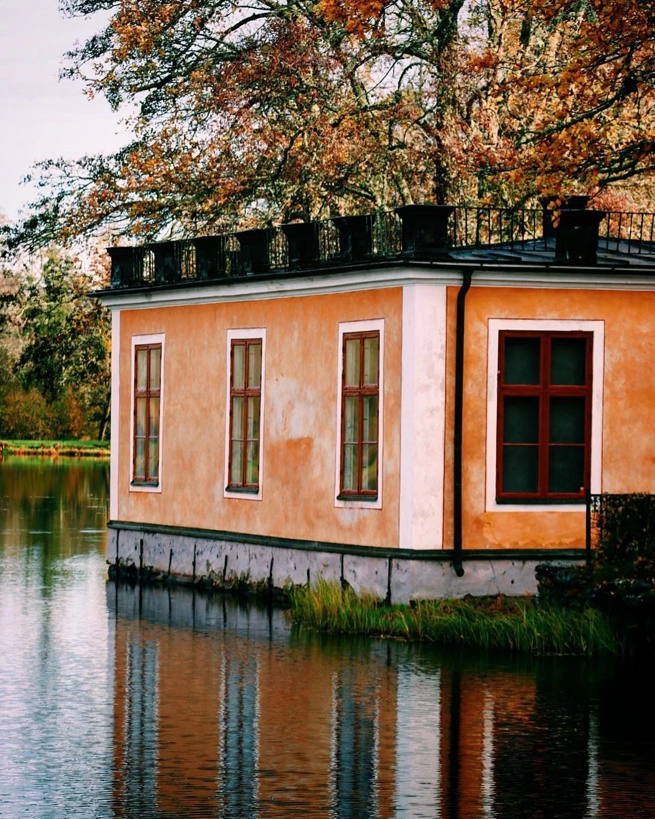 1700-tals biblioteket i Lövstabruk
En gul-orange hus vid vattnet med tre smala fönster och ett större fönster, omgivet av träd med höstlöv.