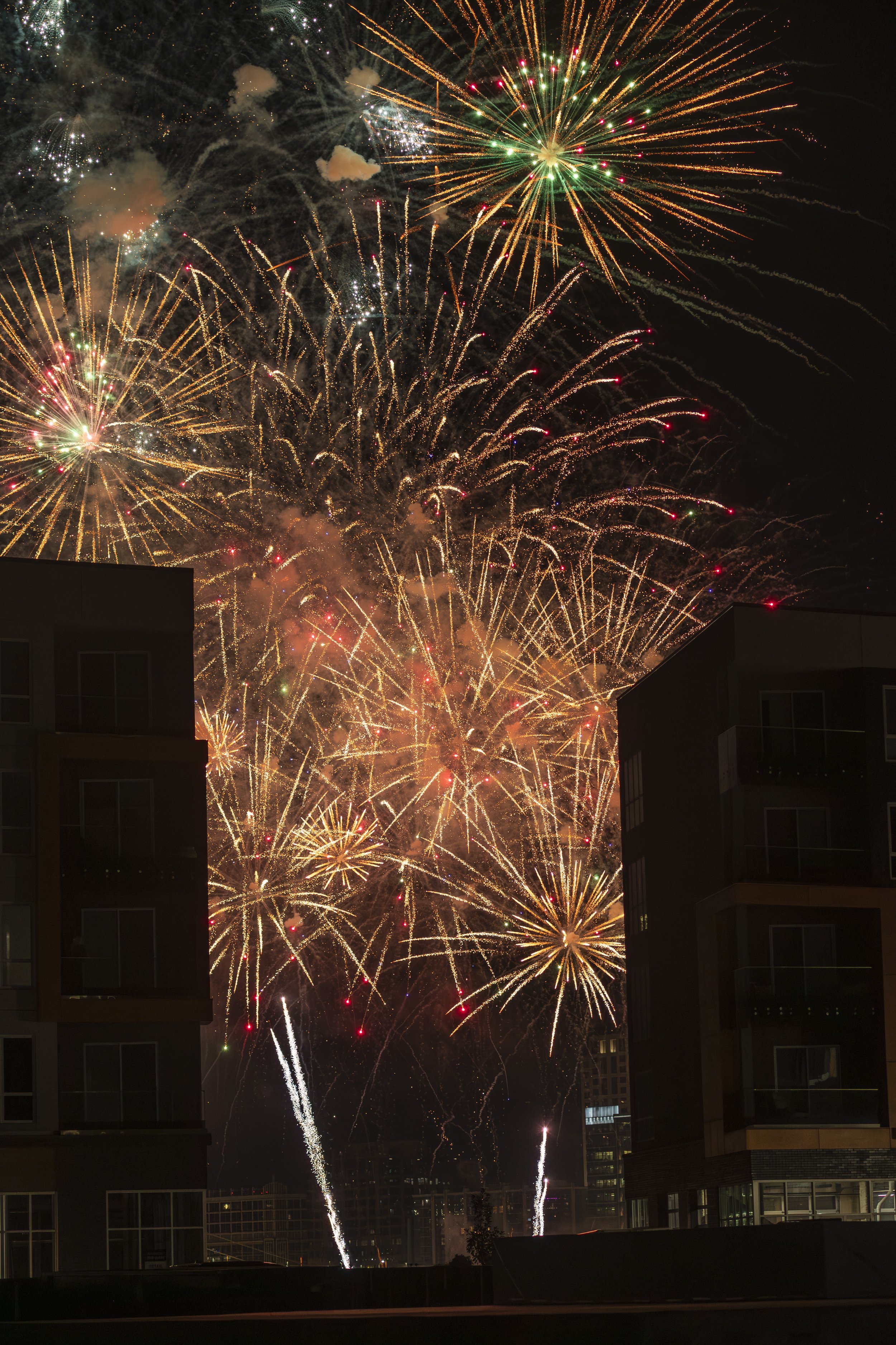 Fireworks display lighting up the night sky over buildings.