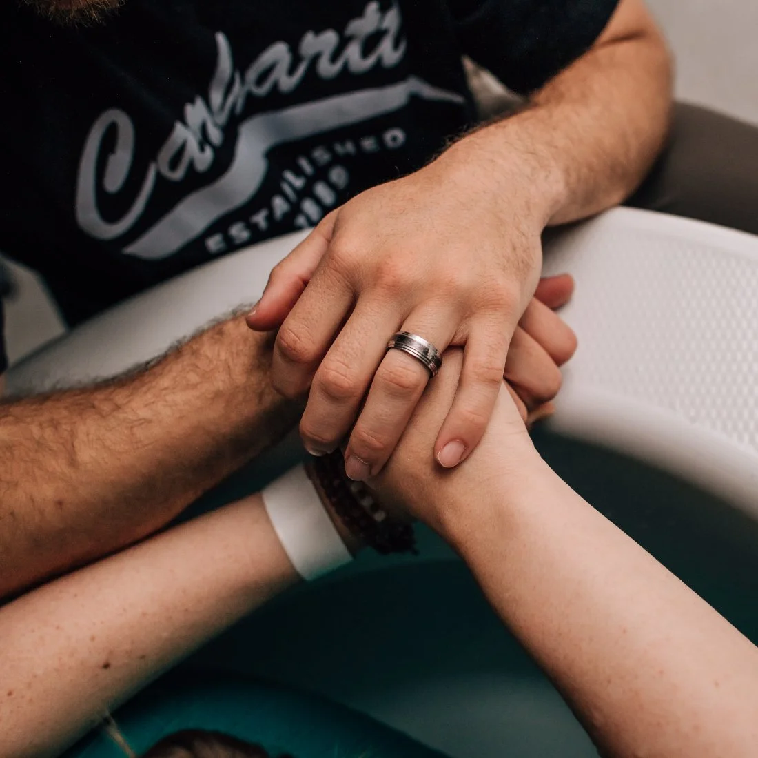 Hands clasped together in quiet support during labor with a Trauma Informed Doula offering reassurance