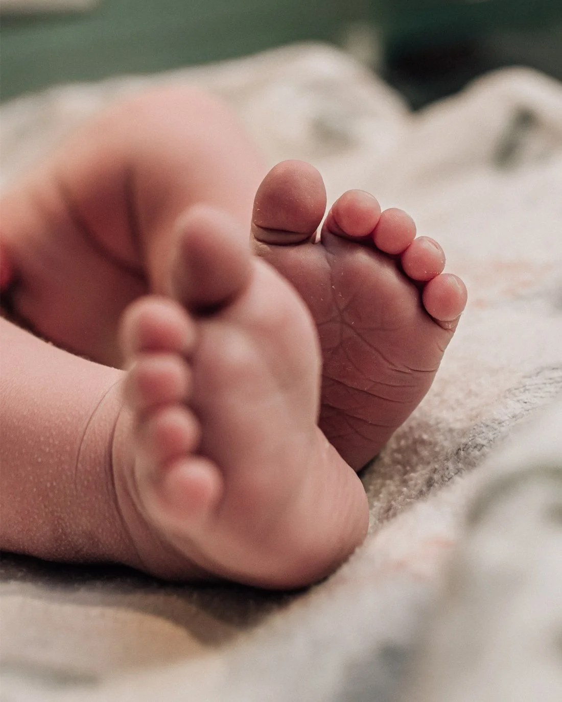Close up of newborn baby feet resting on a blanket, representing immediate newborn care choices included in a birth plan checklist.