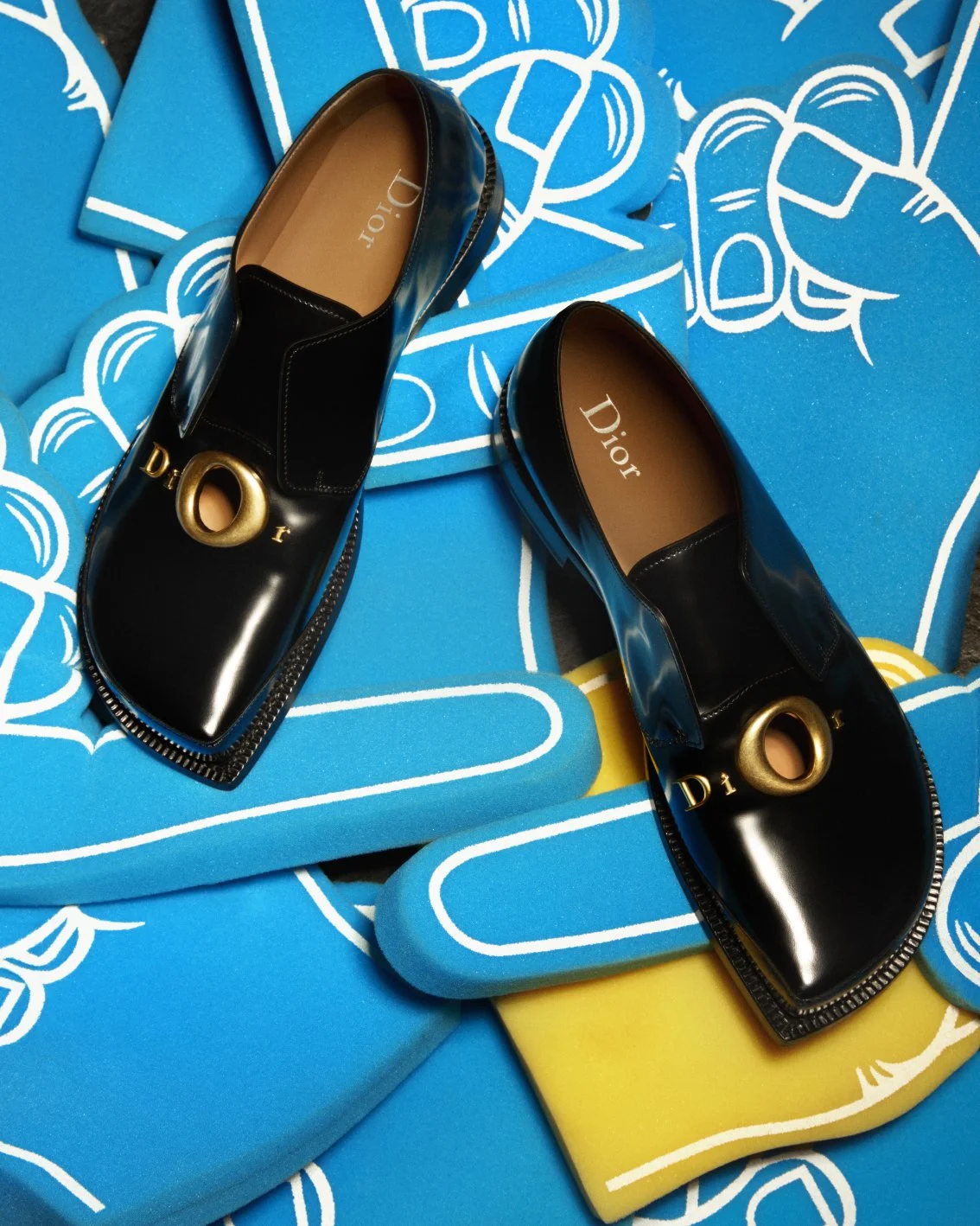 Luxury Dior shoes placed on top of blue and yellow foam hands
