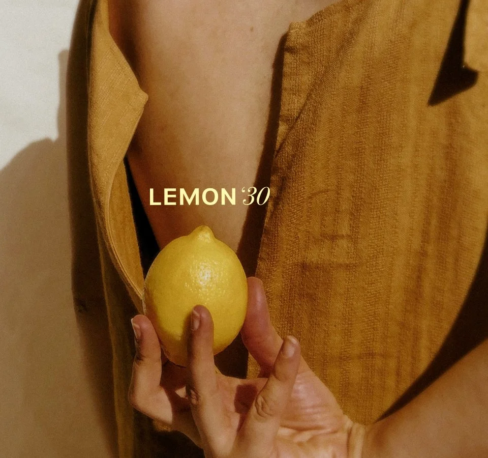 Una persona tiene in mano un limone, che è stato etichettato come 'LEMON 30', con una camicia marrone.