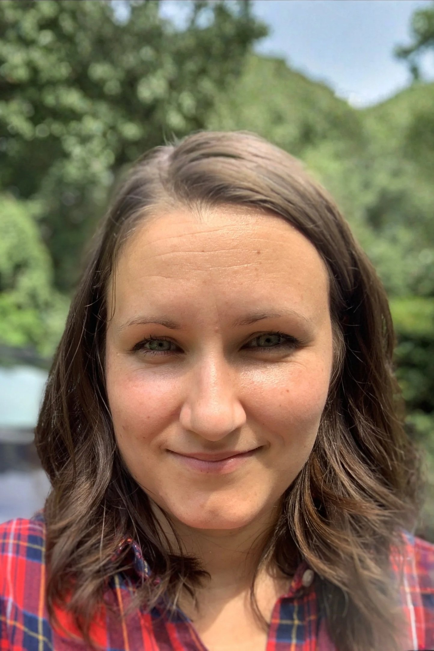 Dr. Sarah Backe is pictured in front of green trees and blue skies. Dr. Backe is a pediatric neuropsychologist who conducts neurodiversity-affirming evaluations. She specializes in ADHD, autism, anxiety, depression, and learning disabilities.