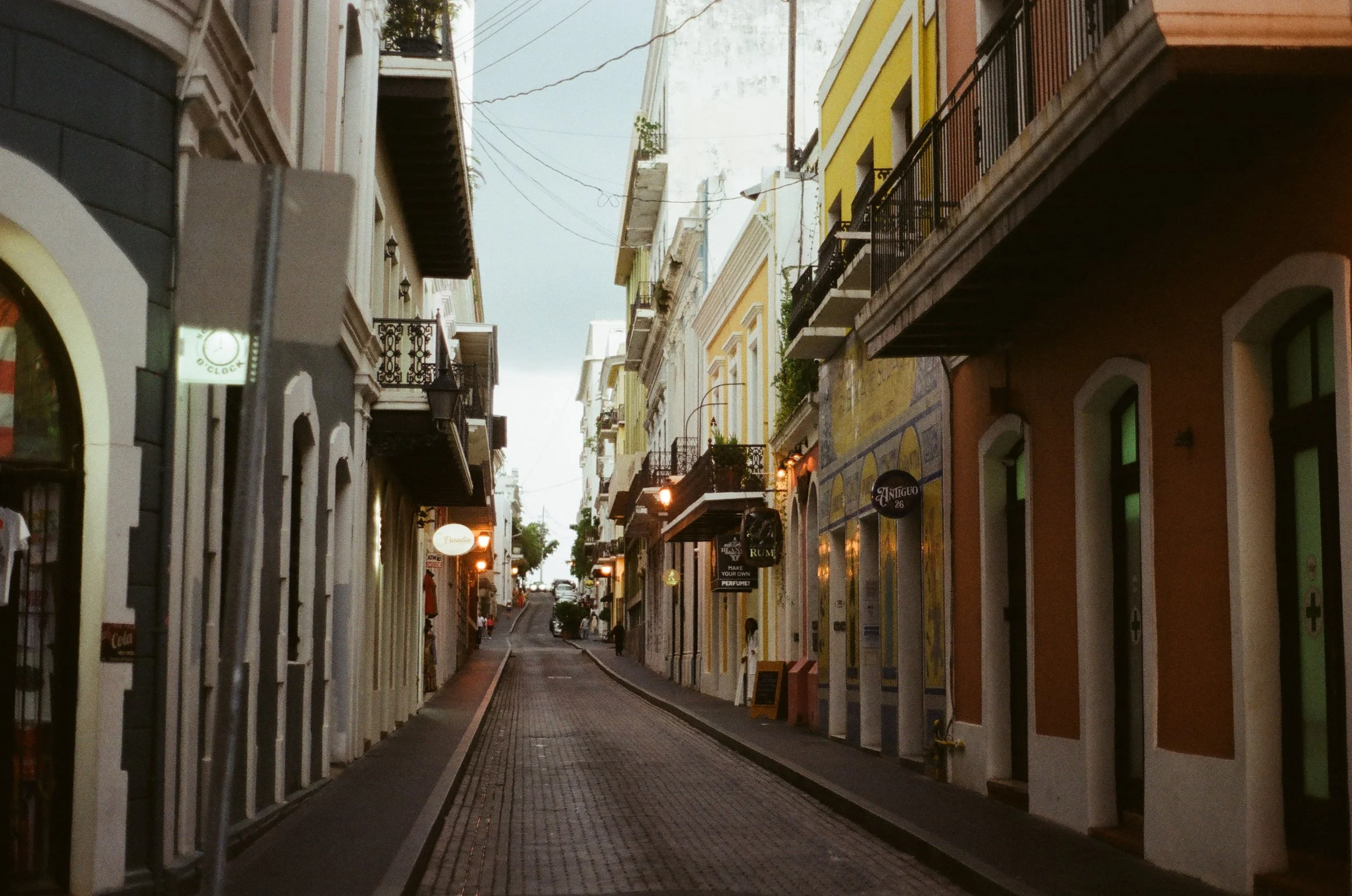 narrow cobblestone street lined with colorful colonial-style buildings and balconies