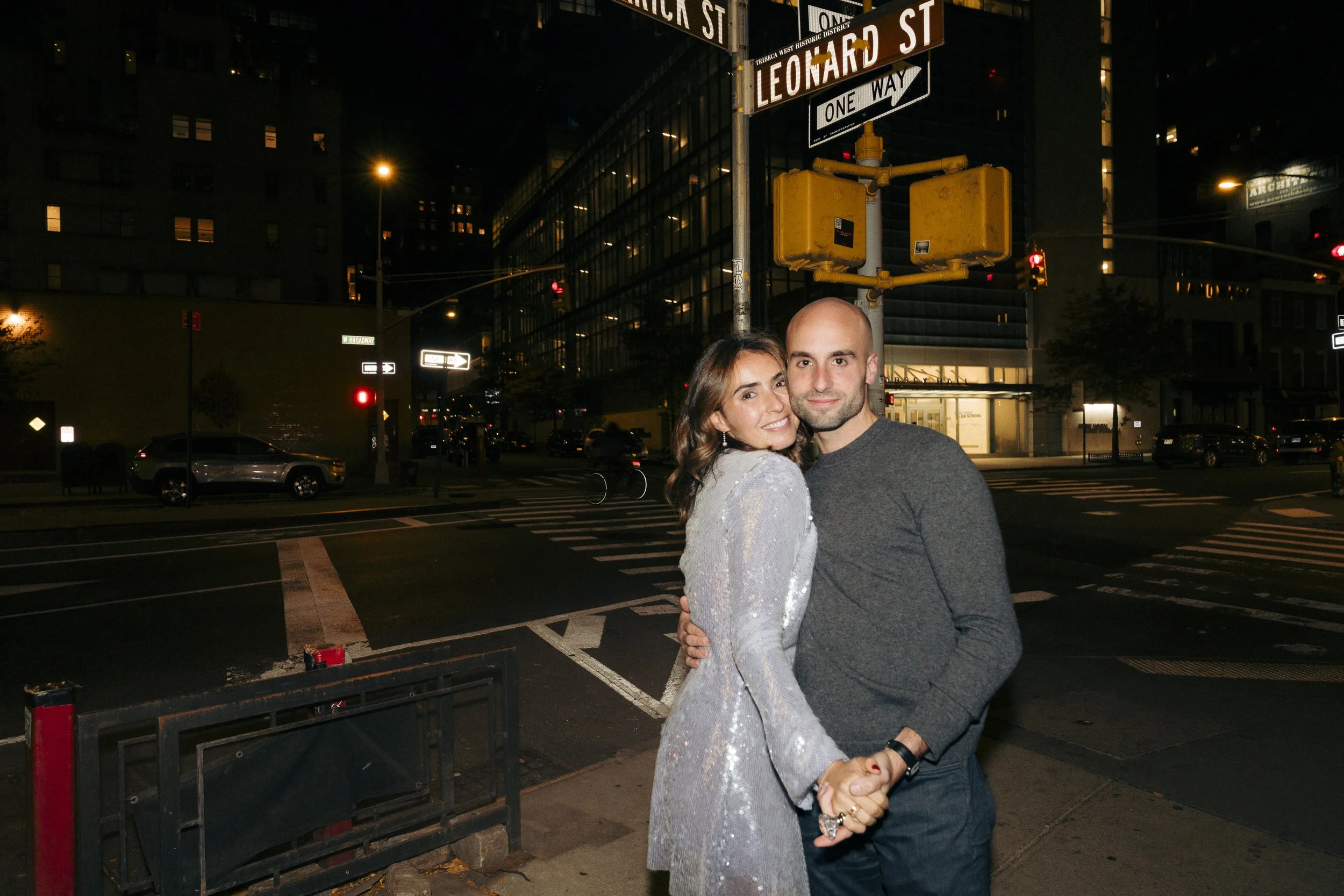 Couple embracing at urban street corner, night scene with street signs and traffic lights Square Diner in New York City