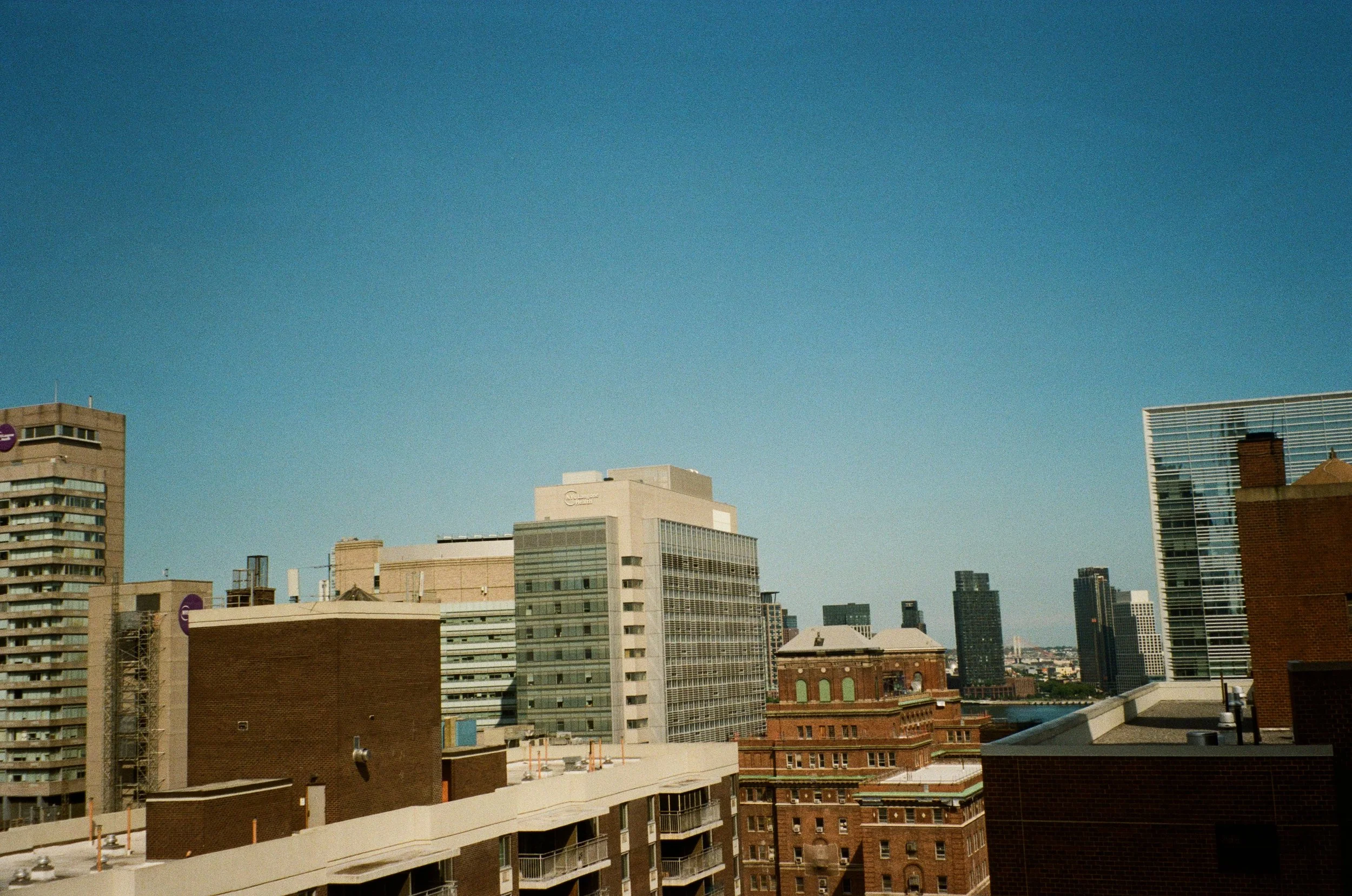 City skyline with various modern buildings under a clear blue sky.