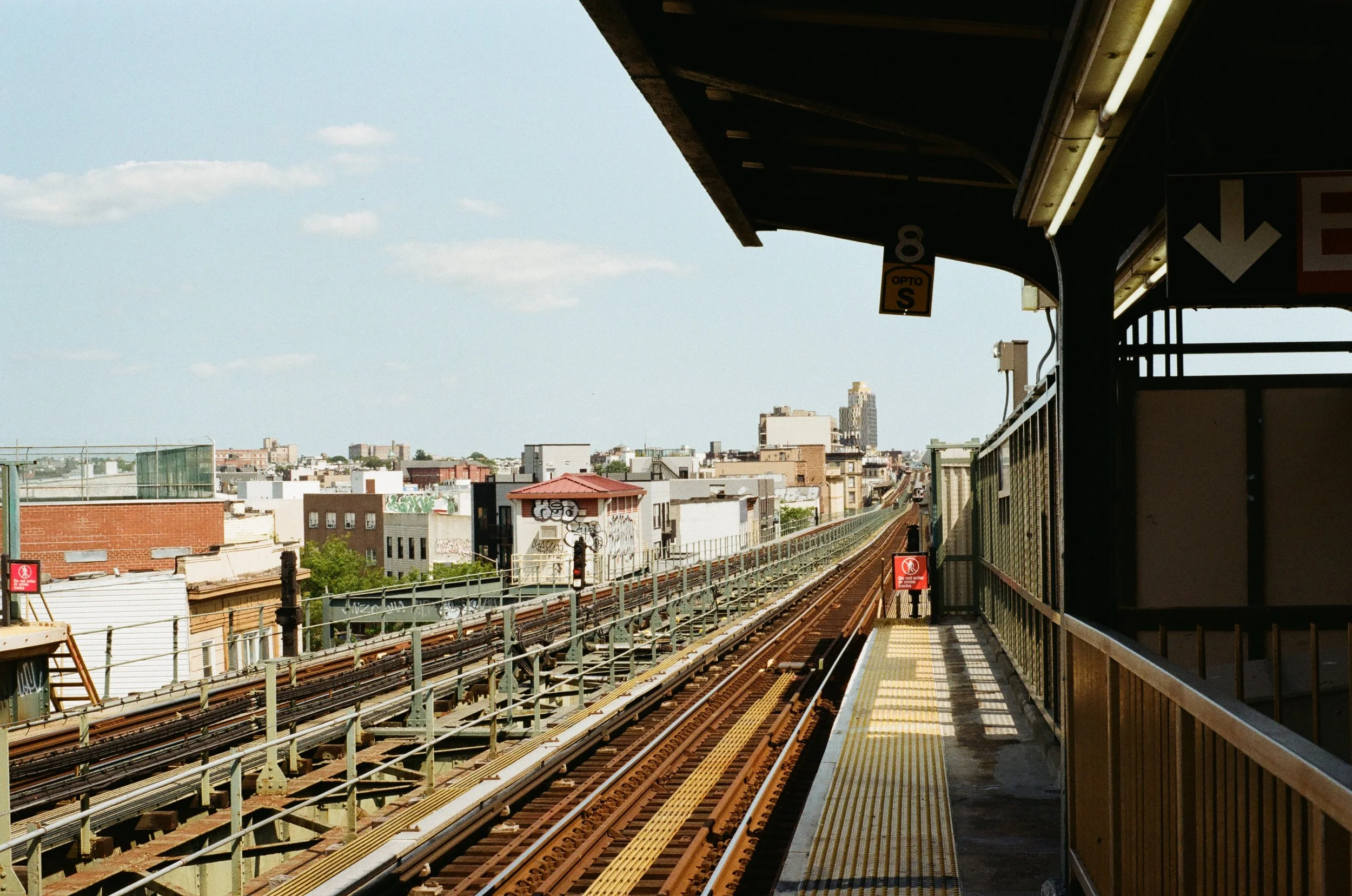 Urban elevated train tracks with view of city skyline and rooftops.