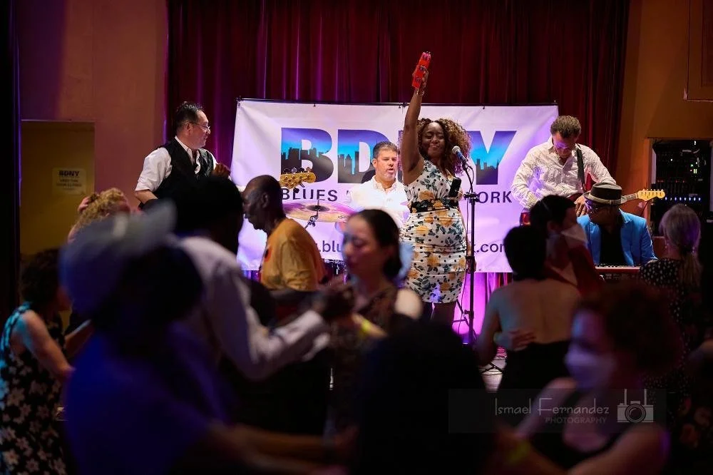 Seydurah Avecmoi singing with a band in front of a BDNY banner