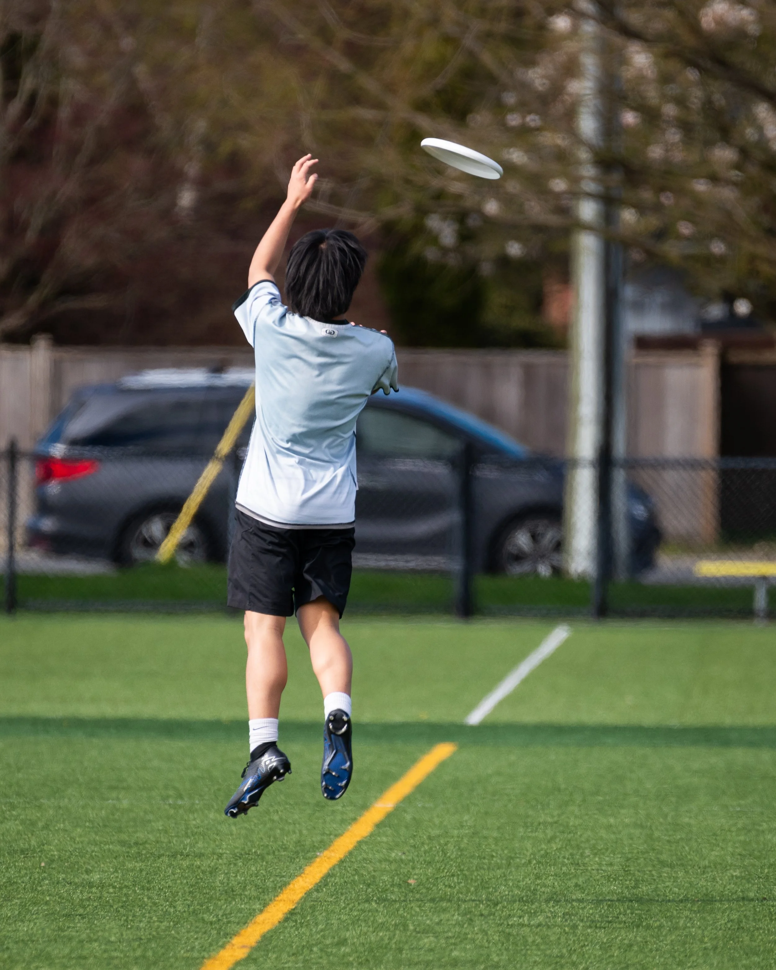 A person in athletic clothing jumping to throw a frisbee on a grassy field.