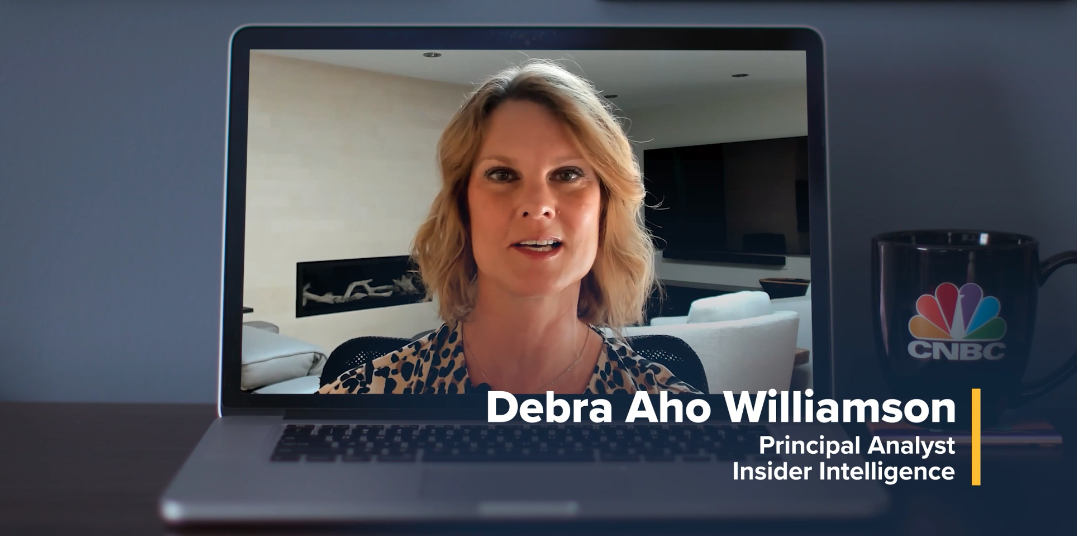 A laptop screen showing a video call with a woman speaking, labeled as Debra Aho Williamson, Principal Analyst at Insider Intelligence. A CNBC-branded mug is visible next to the laptop.