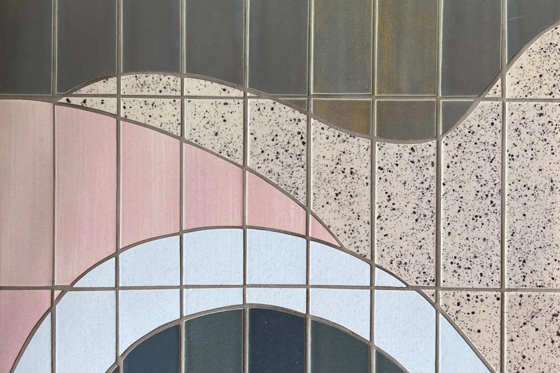 Close-up of a decorative tiled surface with pastel pink, blue, and speckled patterns, arranged in geometric shapes.