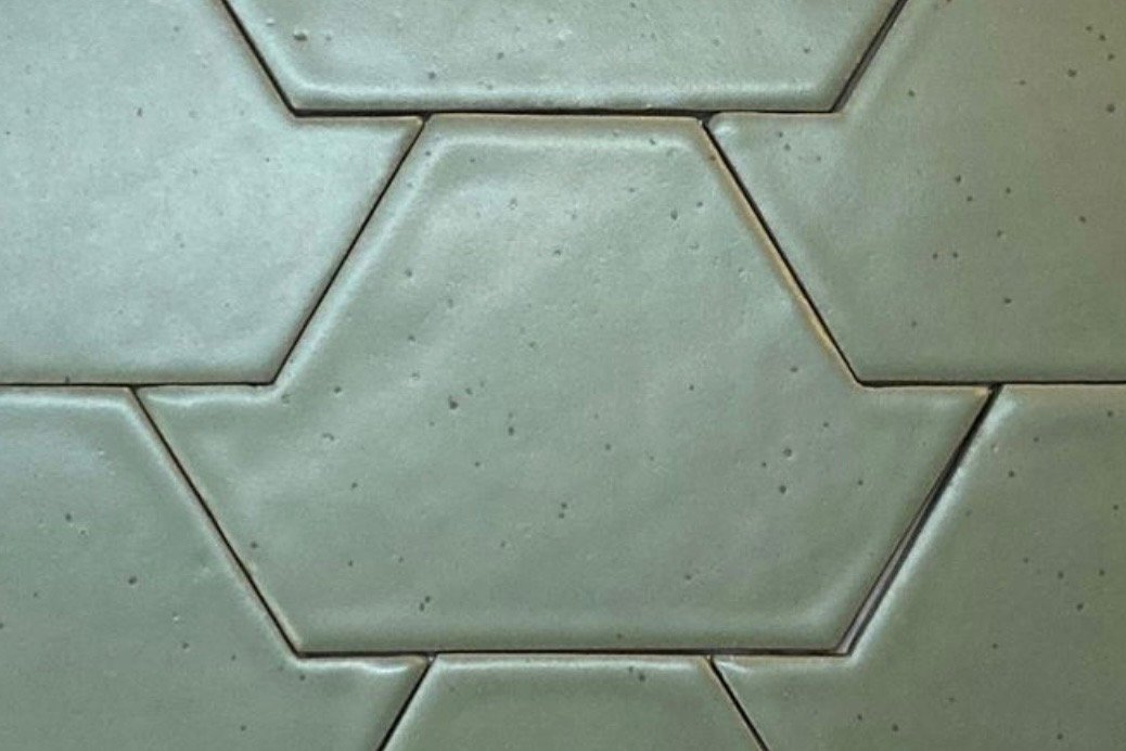 Close-up of light green hexagonal tiles on a floor or wall.