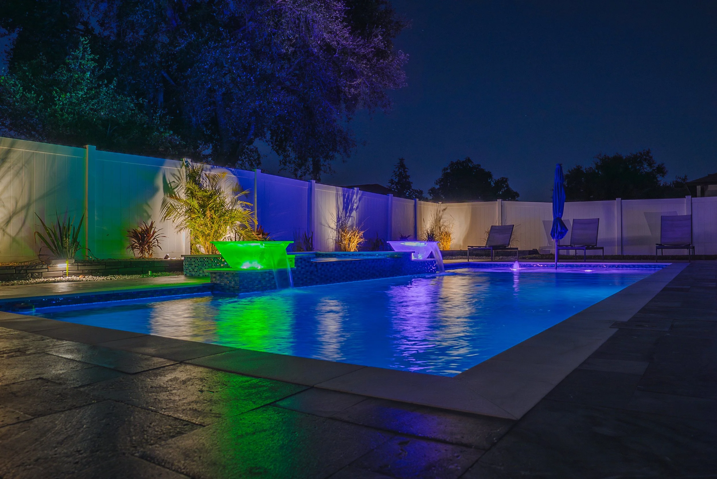 New pool and spa at night with LED lighting, waterbowls and lounge area