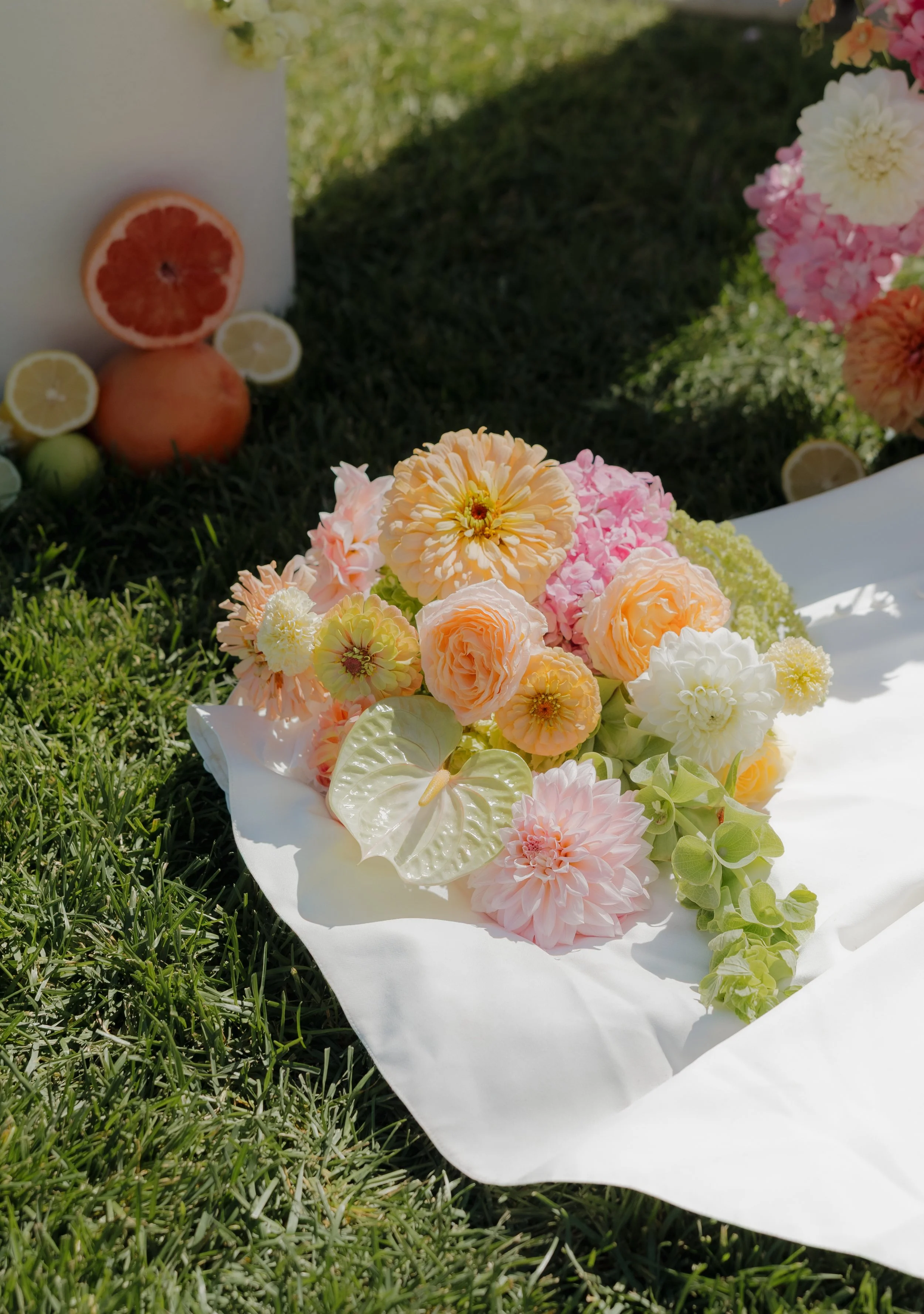 Colorful flower bouquet with cut citrus fruits and some green fruits on grass, located in DFW, Texas.