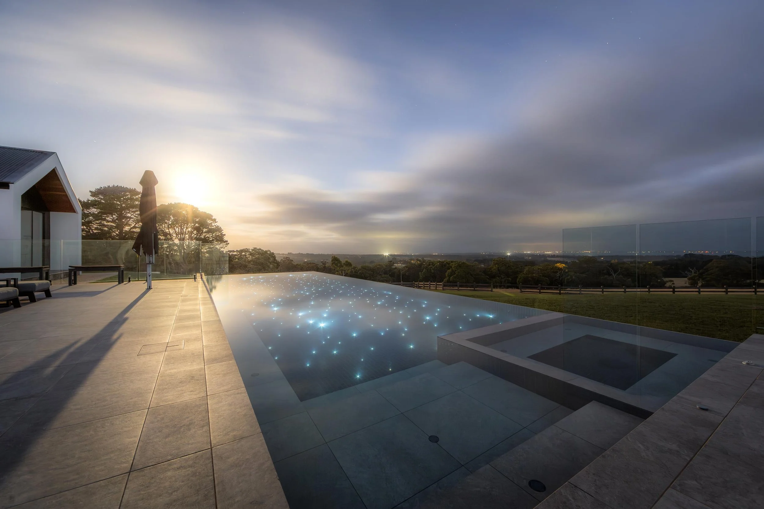 Pool with starlight-inspired lighting overlooking a vast backyard meadow