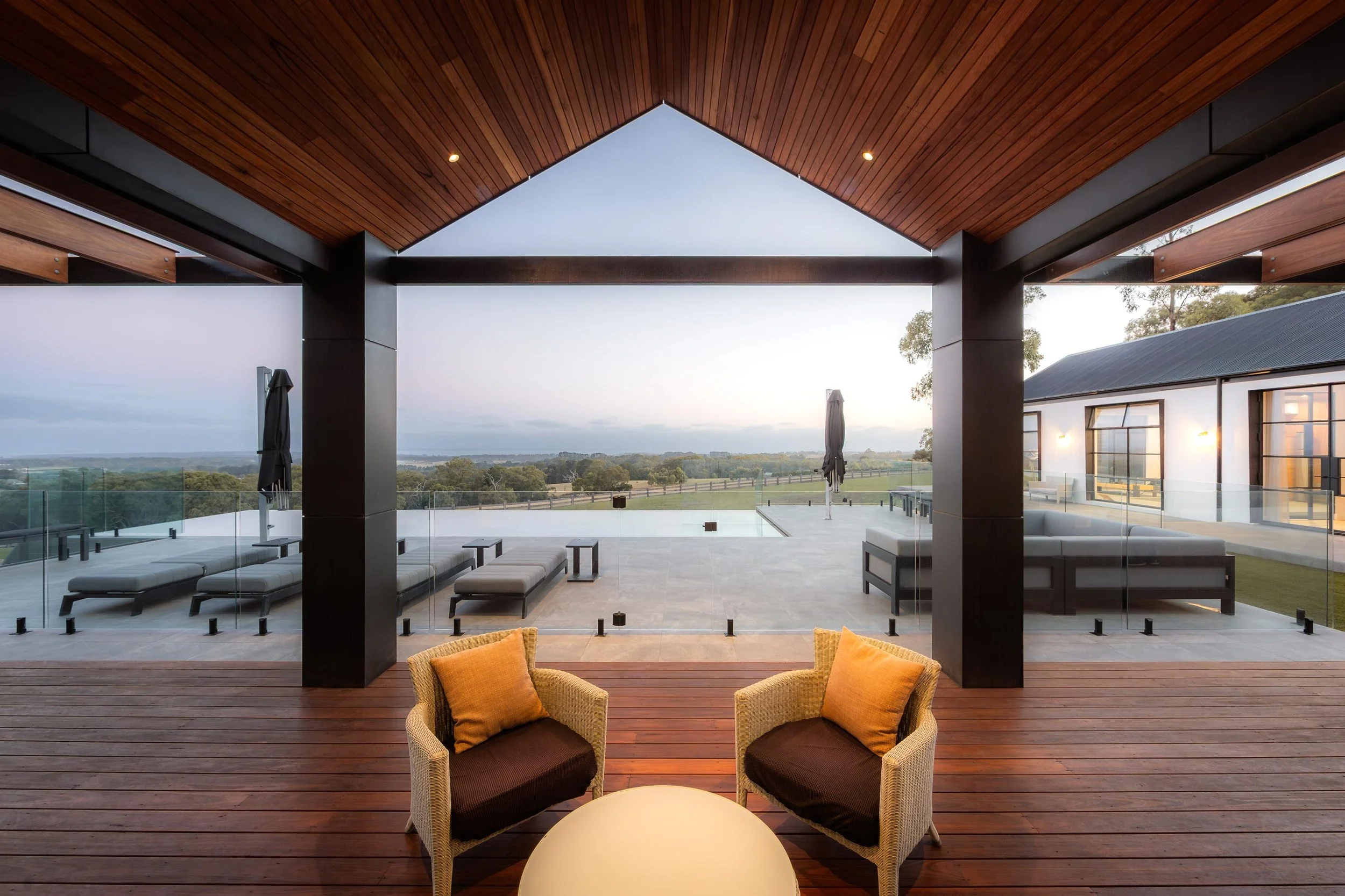 Semi-outdoor timber pavilion with outdoor seating and direct access to a backyard swimming pool.