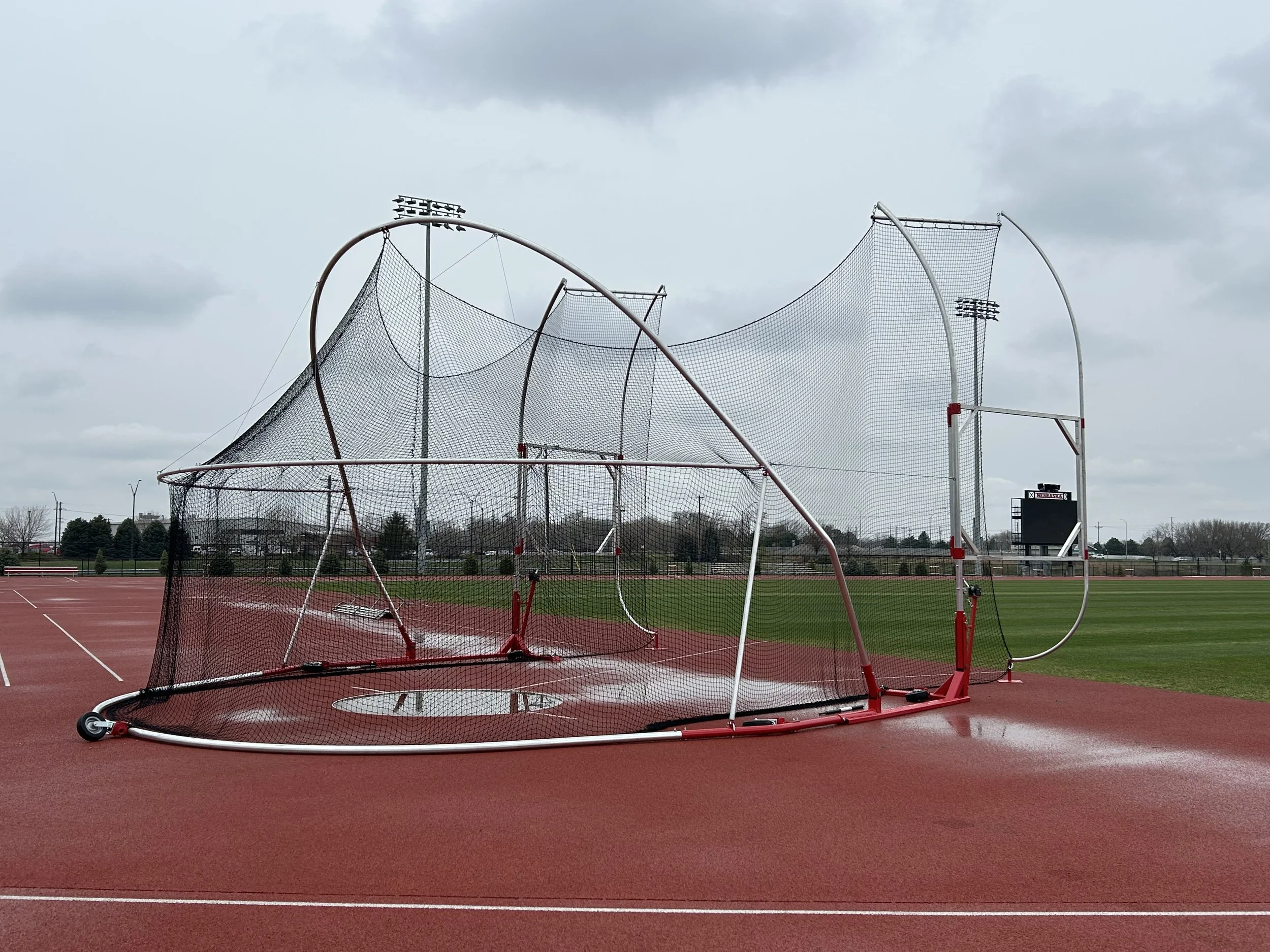 Scenic lake with mountains and grassy hills in the background under a cloudy sky.