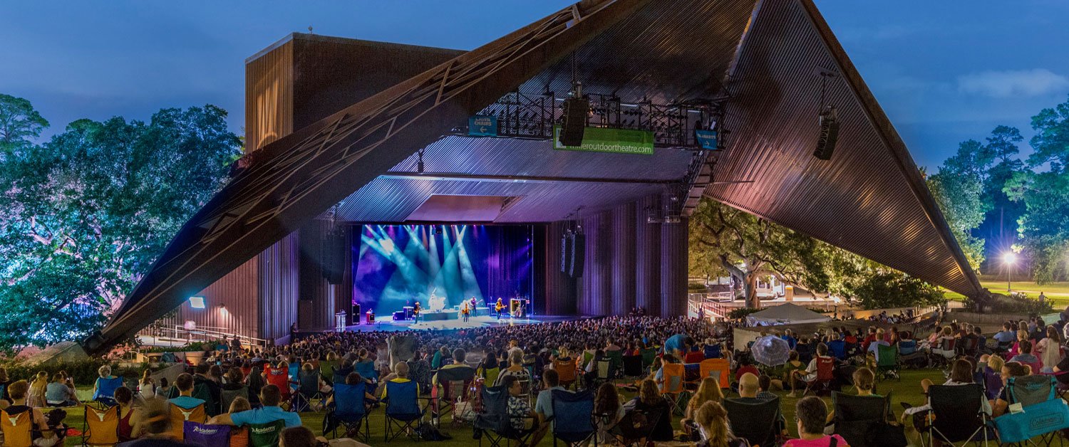 Outdoor theatre lit up with band on stage and audience watching