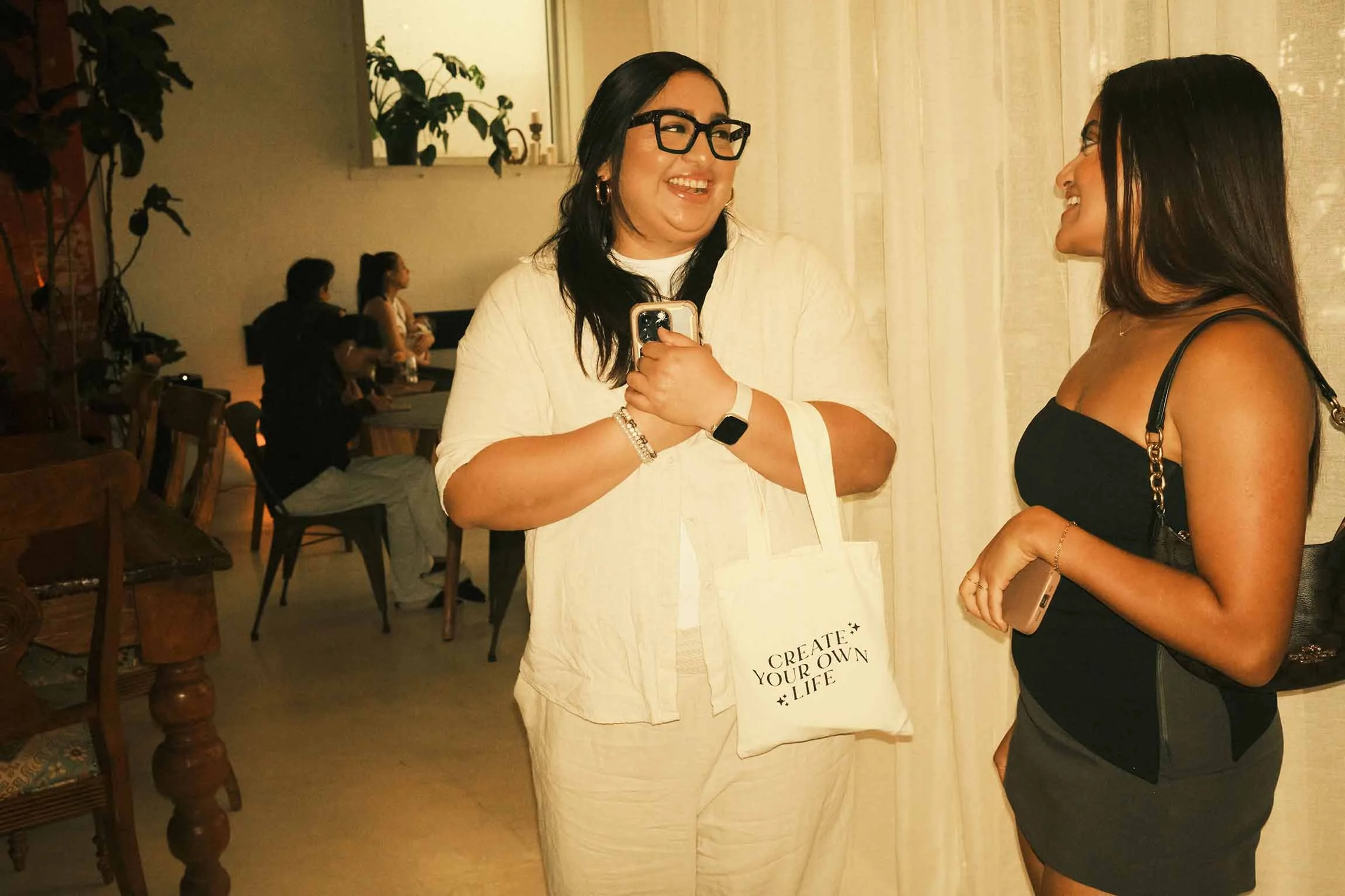 Two Latina influencers smiling and connecting at a Houston creator engagement event