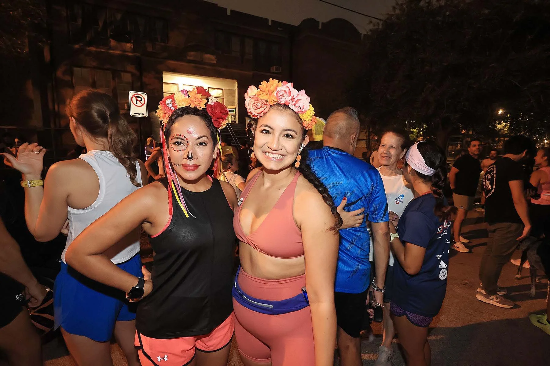 Two Latina women wearing floral crowns at a Houston Día de los Muertos cultural event activation