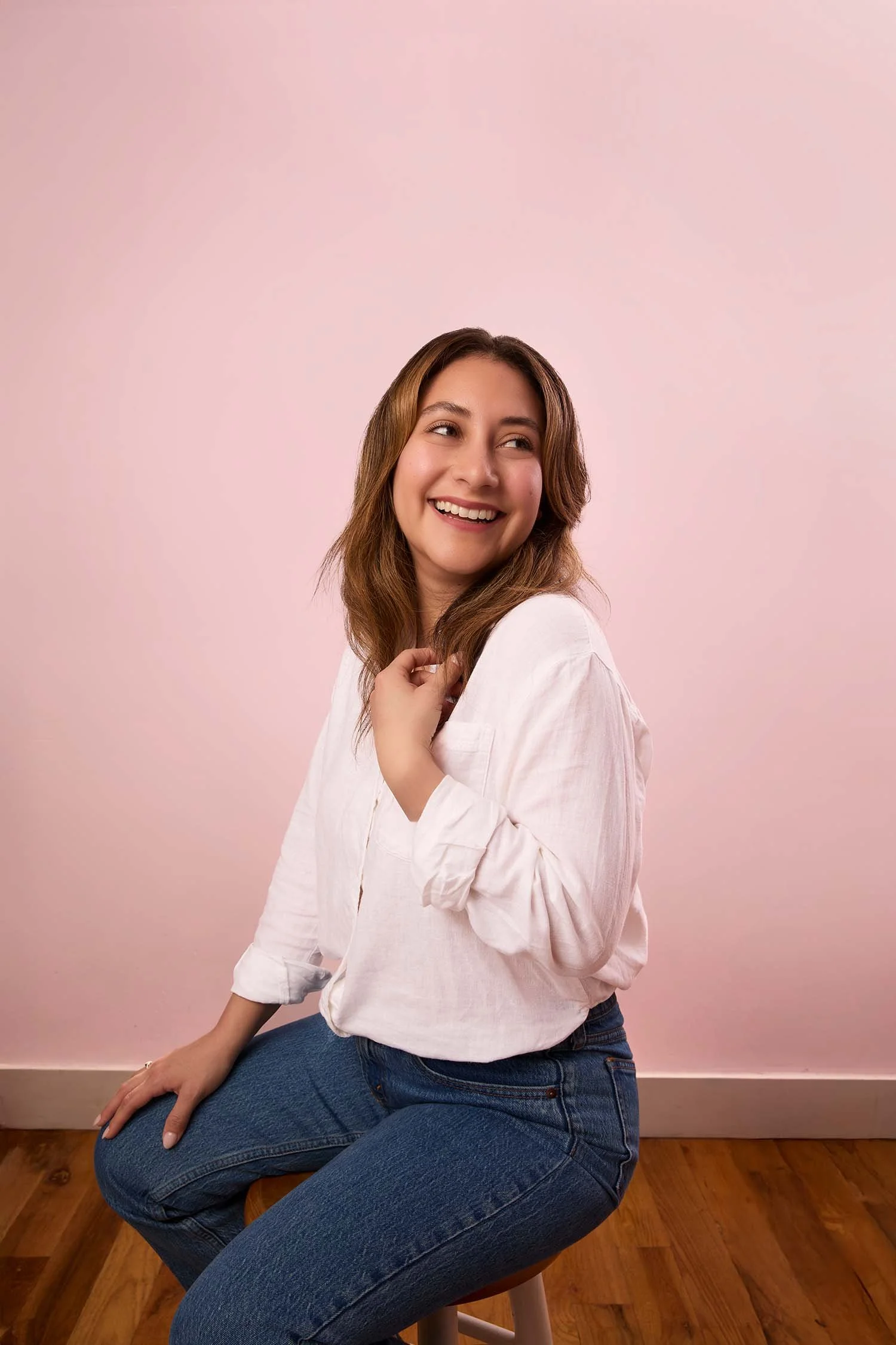 Rosa Pruneda, Latina PR consultant and Houston communications strategist, smiling warmly in a professional studio portrait with a pink background